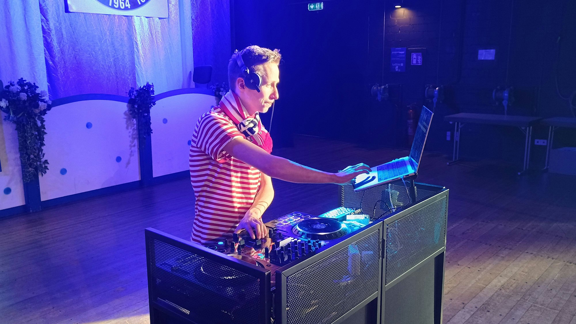 Der DJ hantiert mit einem Mischpult und einem Laptop auf der Bühne.