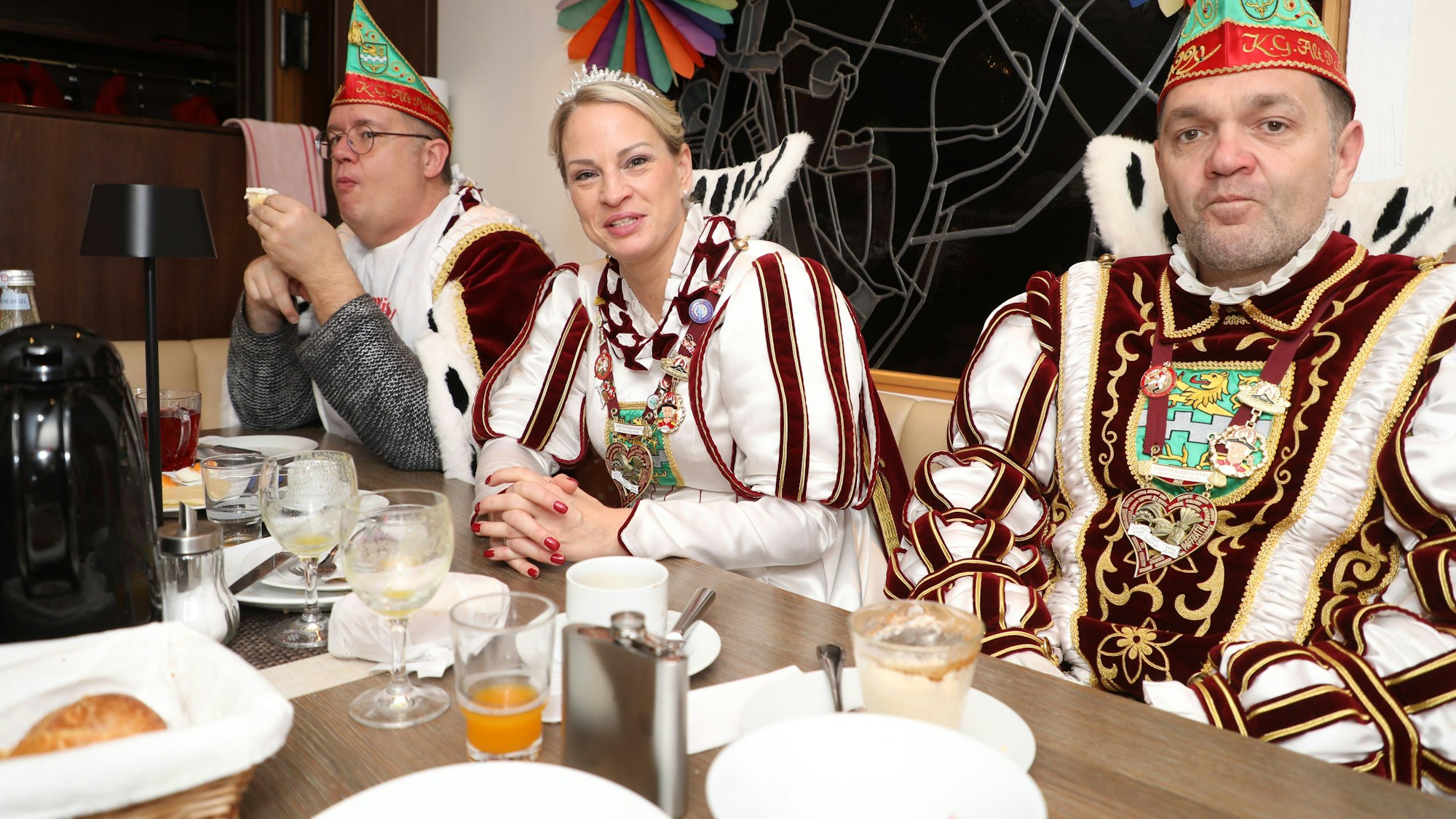 Jungfrau Steffi vom Bergisch Gladbacher Dreigestirn sitzt beim Frühstück zwischen Prinz Christian I. und Bauer Michael.