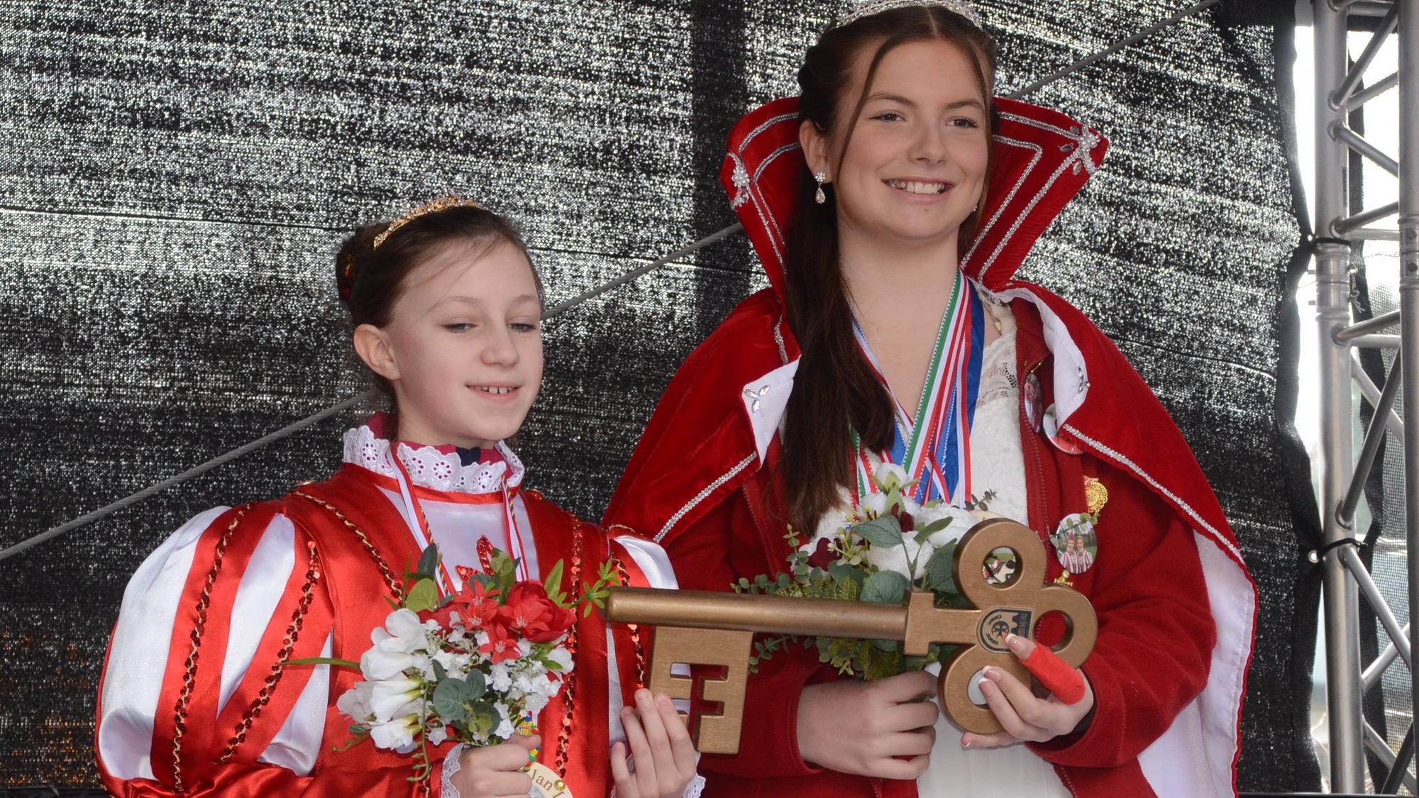 Zwei Mädchen im Ornat von Karnevalsprinzessinnen in Rot und Weiß