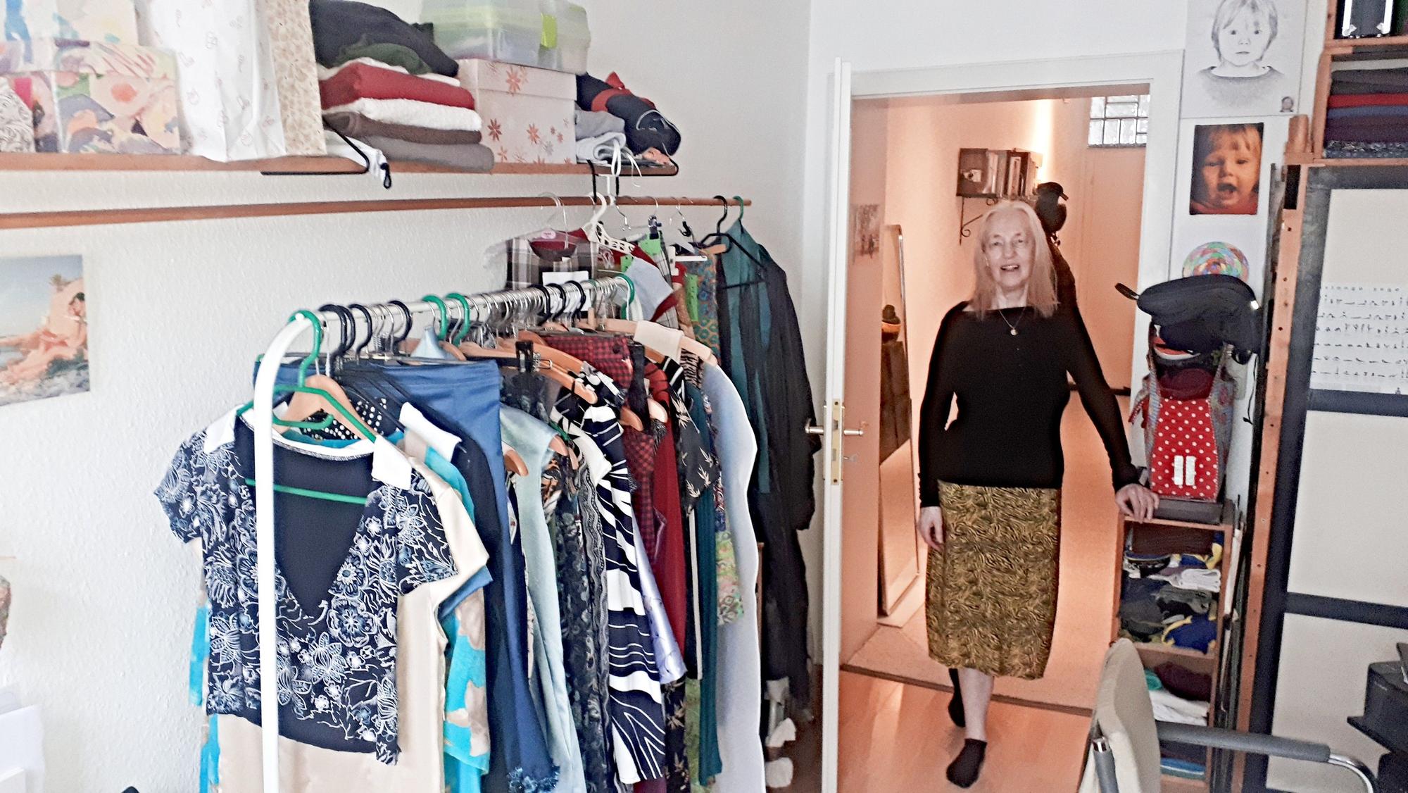 Eine Frau in Rock und schwarzem Oberteil steht in der geöffneten Tür zu ihrem Atelier.