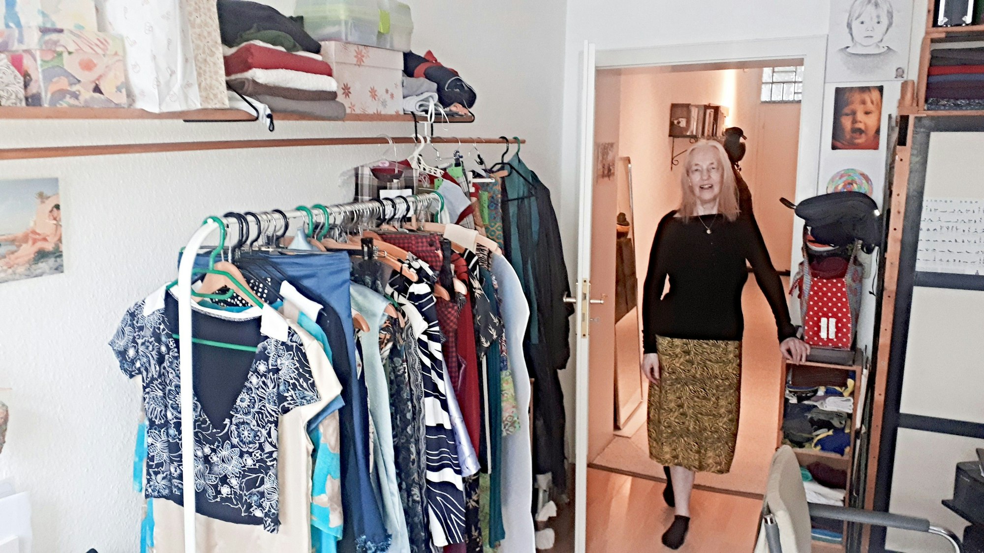 Eine Frau in Rock und schwarzem Oberteil steht in der geöffneten Tür zu ihrem Atelier.