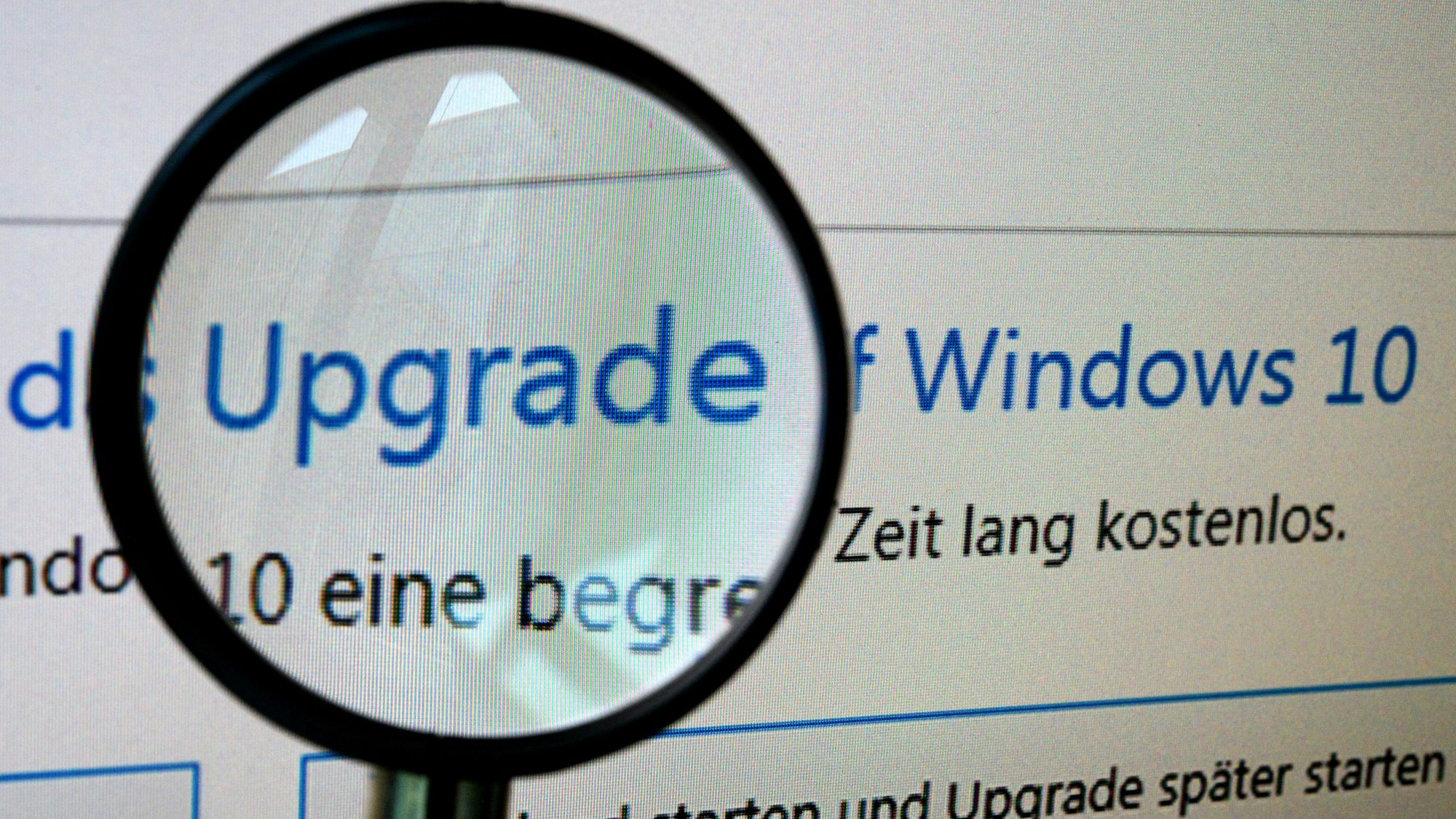 Ein Computerbildschirm zeigt das Update auf Windows 10 mit einer Lupe.