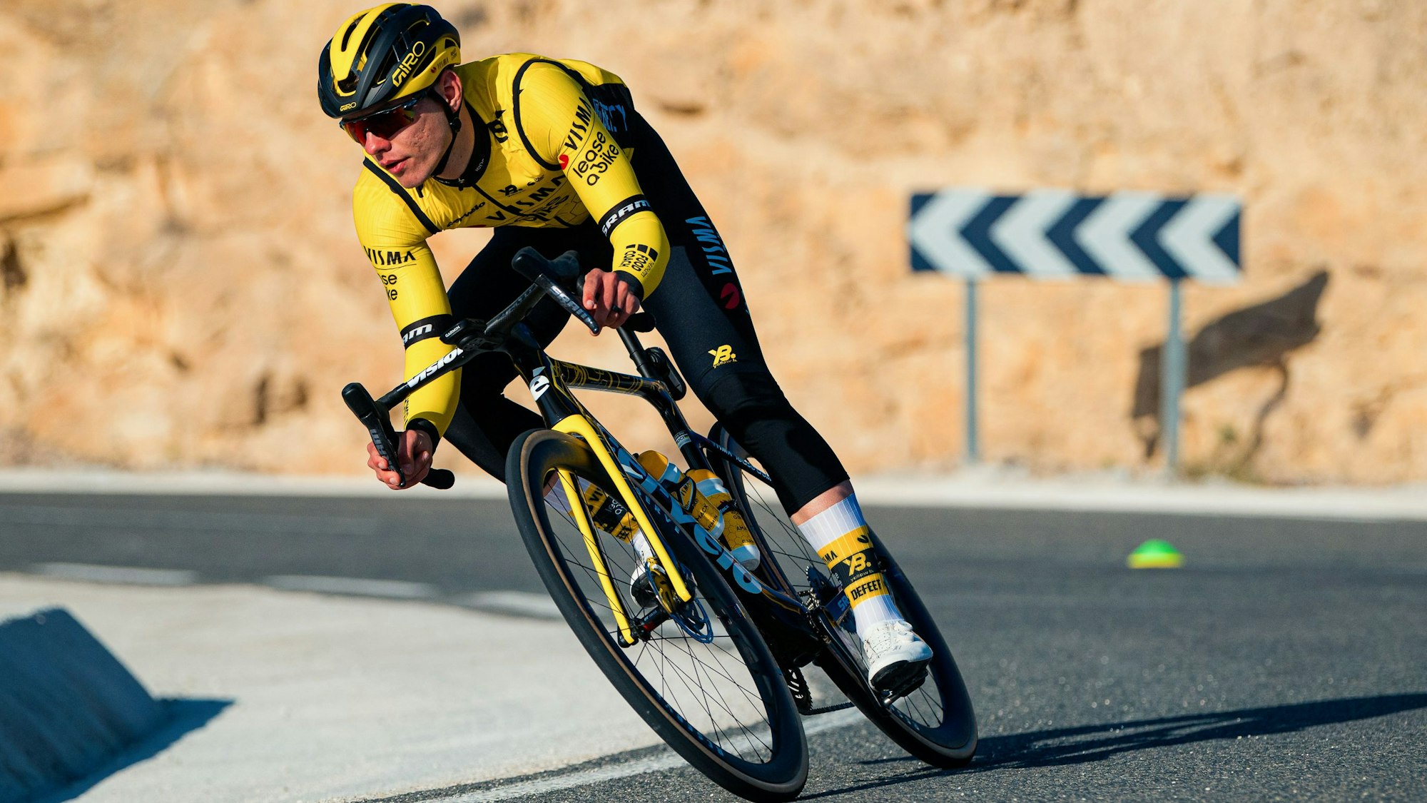 Das Foto zeigt einen Radsportler im gelben Trikot, der in eine Rechtskurve fährt