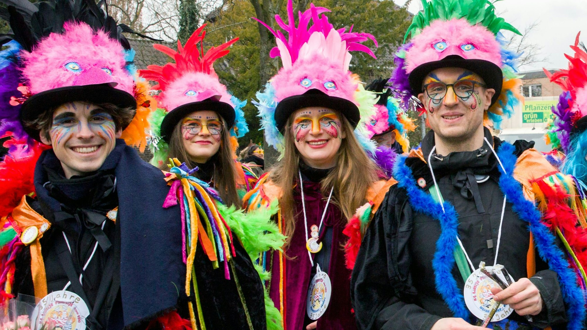 Vier junge Leute in bunten Kostümen lachen in die Kamera.