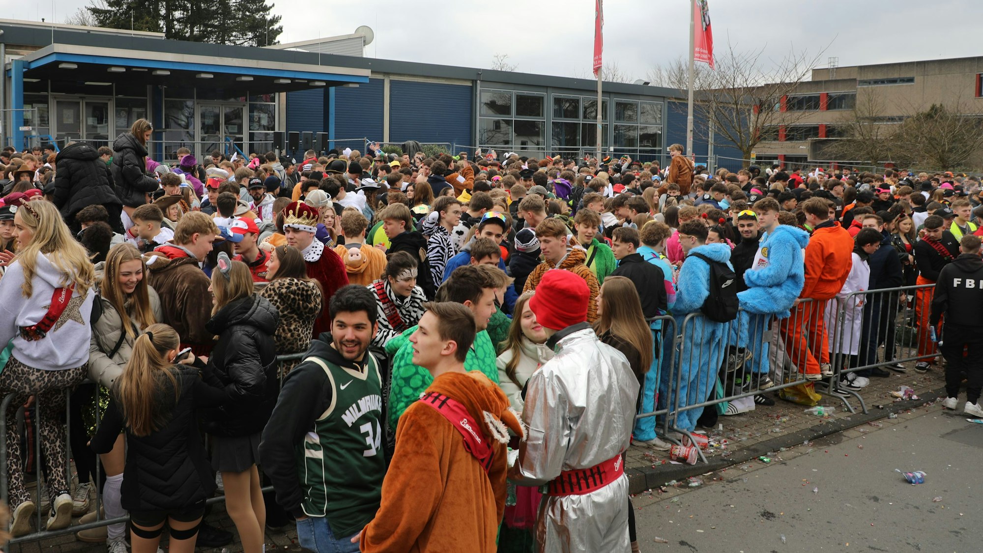 Junge Menschen stehen vor dem Albertus-Magnus-Gymnasium am Bensberger Karnevalszug.