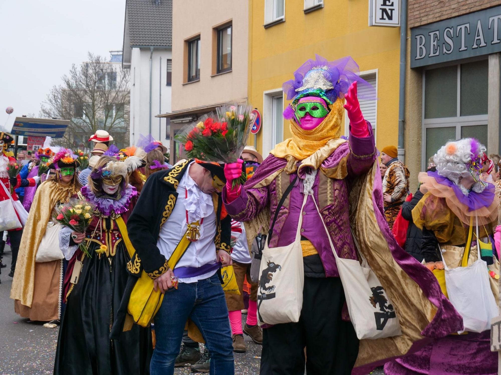 Auf dem Bild ist eine Fußgruppe zu sehen, die venezianische Masken und Kostüme trägt.