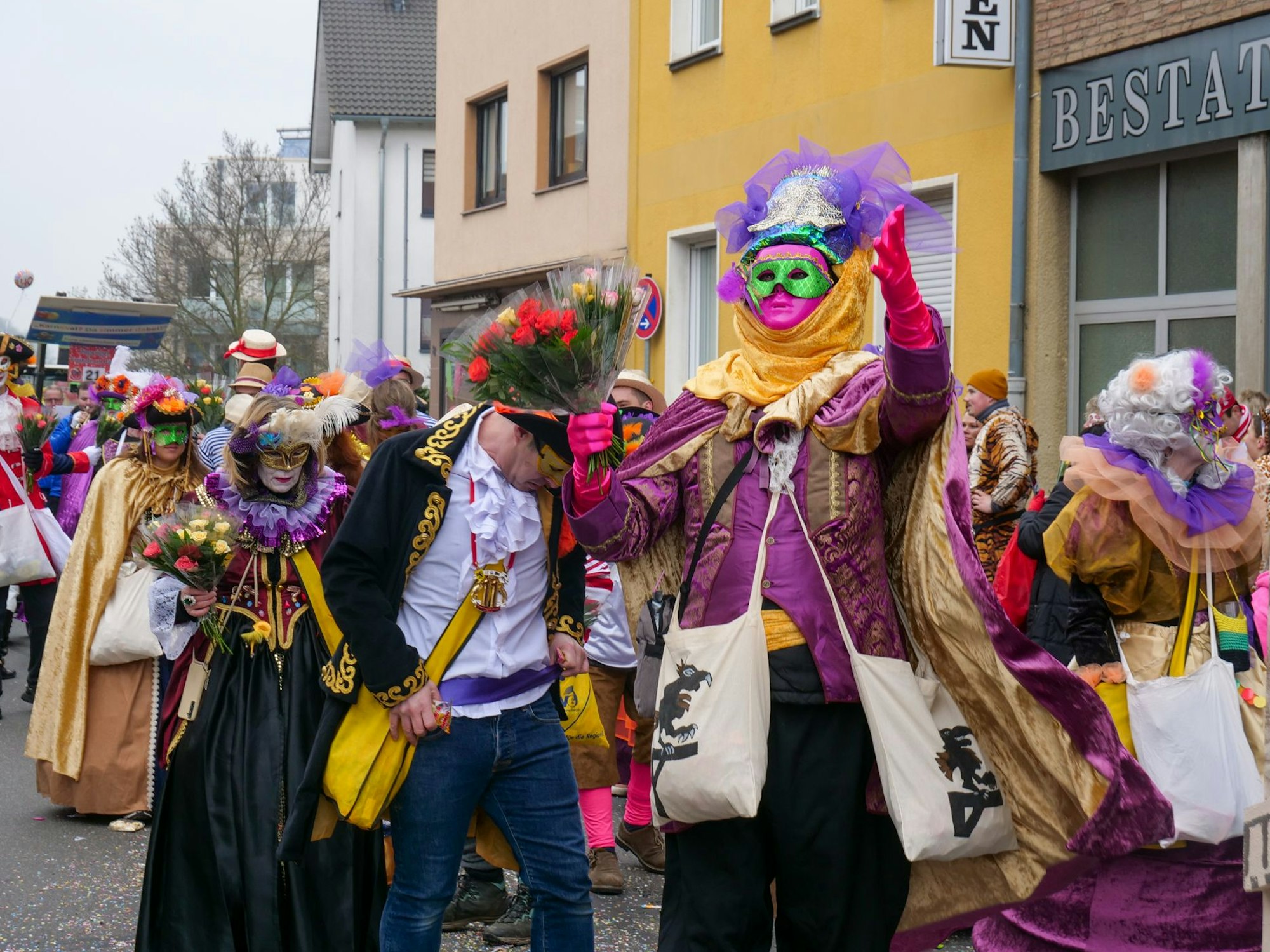 Auf dem Bild ist eine Fußgruppe zu sehen, die venezianische Masken und Kostüme trägt.