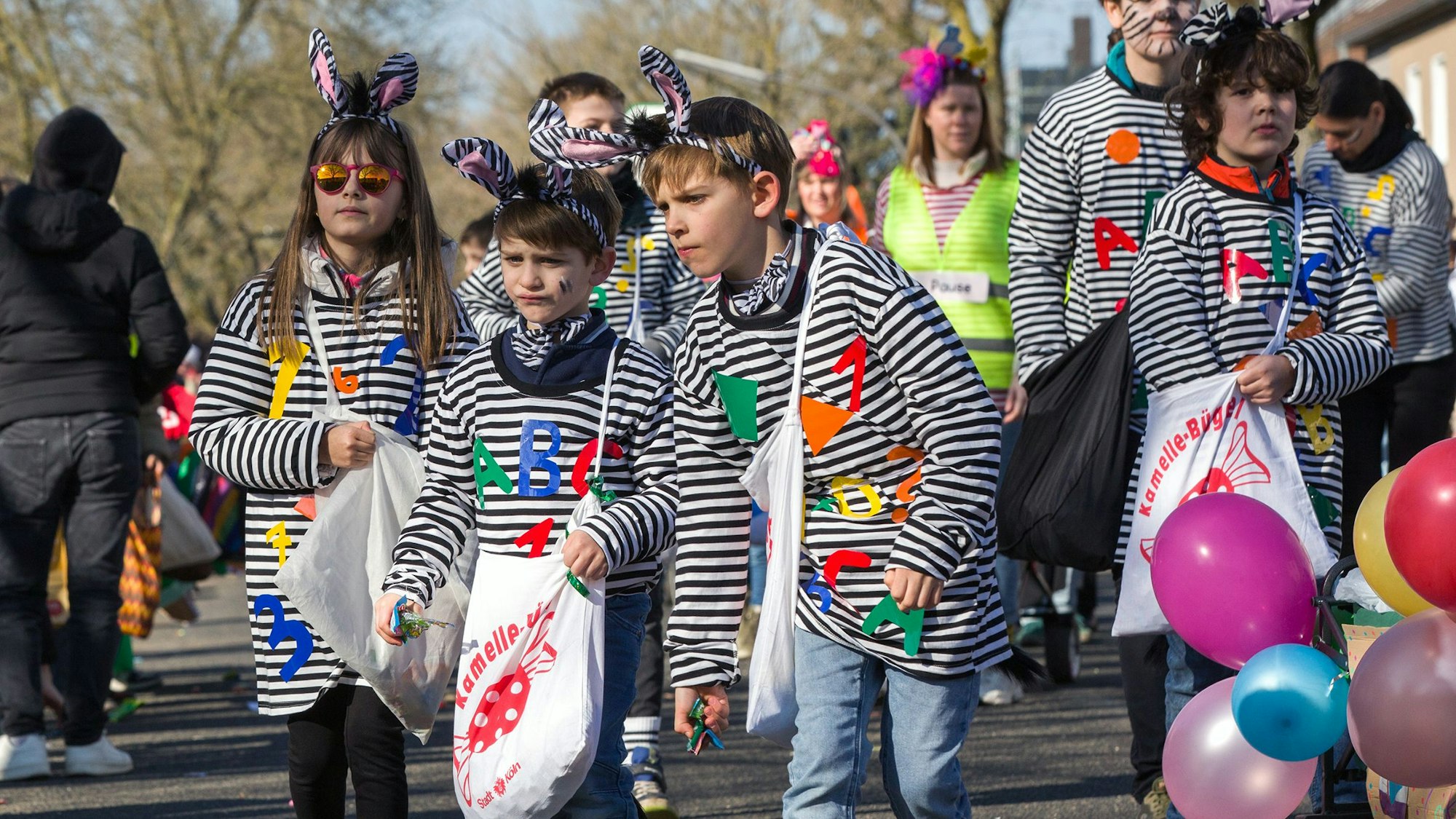 Kinder in Ringelshirts tragen große Kamelle-Büggel.