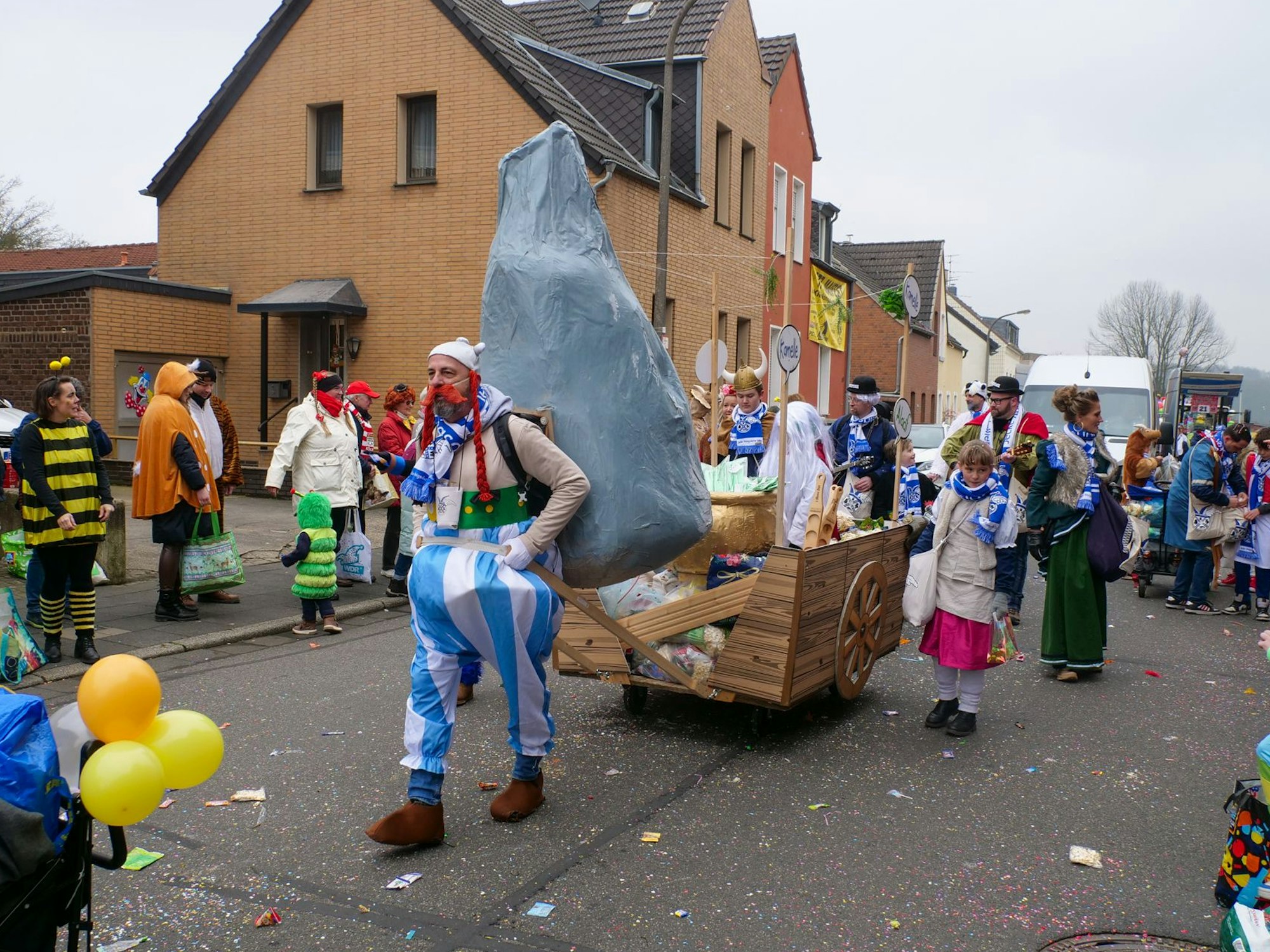 Auf dem Bild ist ein Mann zu sehen, der als Obelix verkleidet ist und einen Wagen zieht.