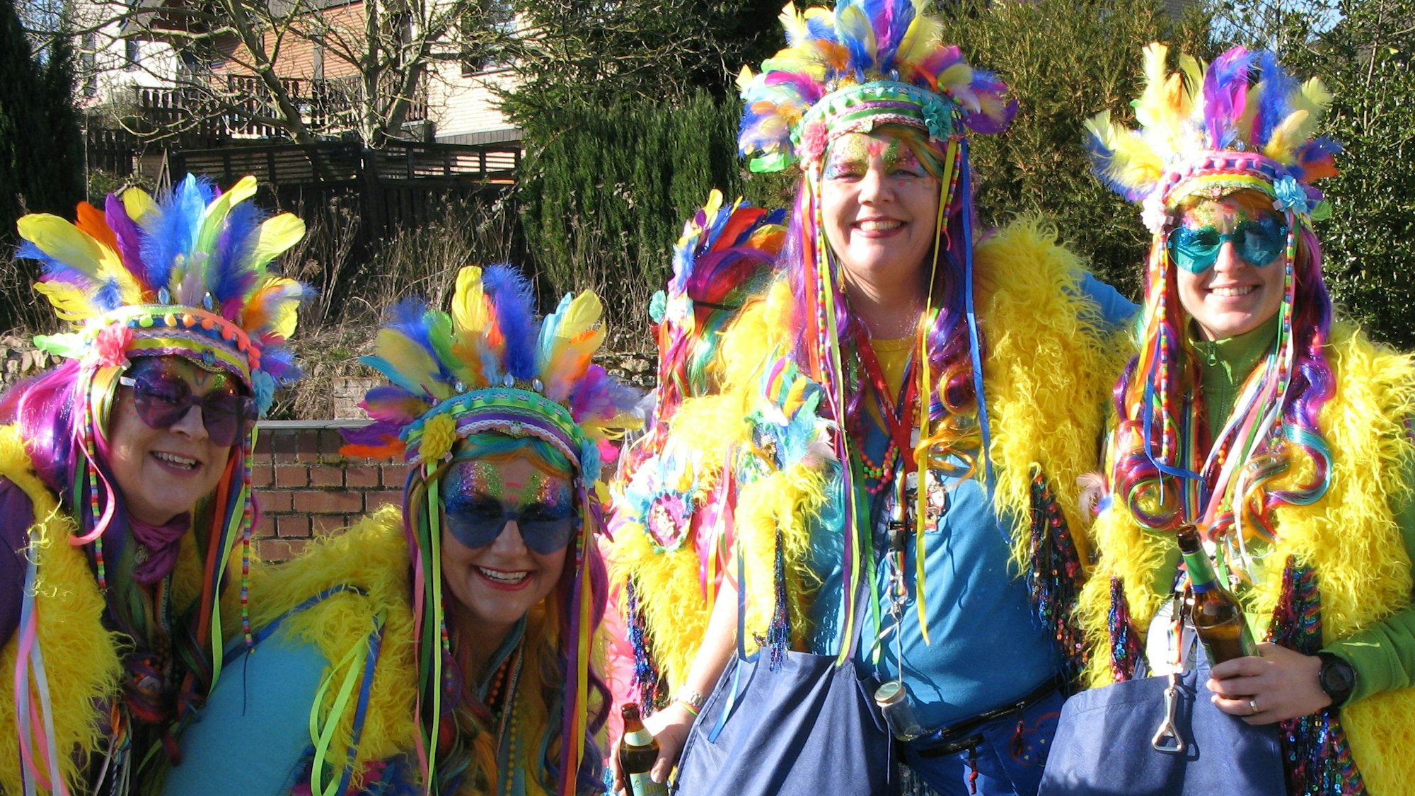 Vier Frauen mit buntem Kopffederschmuck.