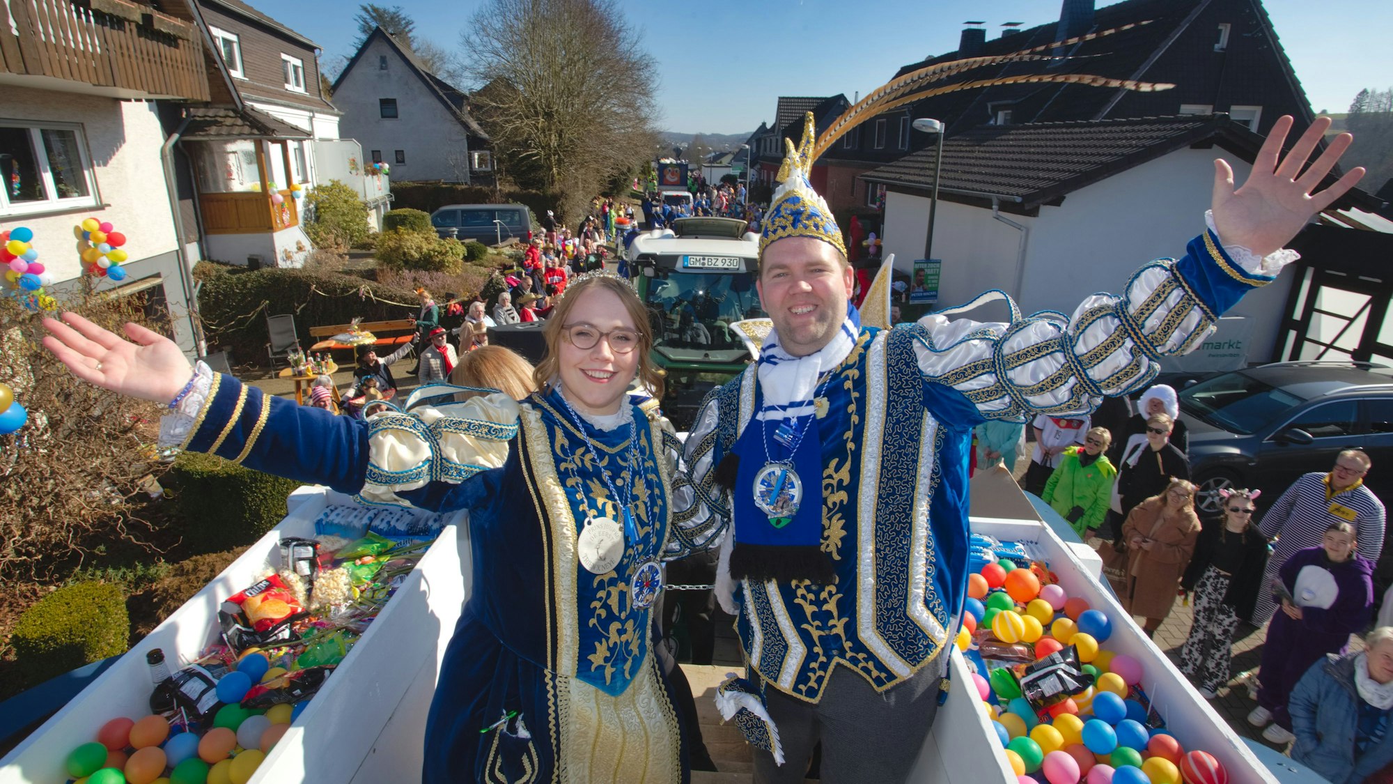 Ein Prinzenpaar bei einem Karnevalszug auf einem Wagen.