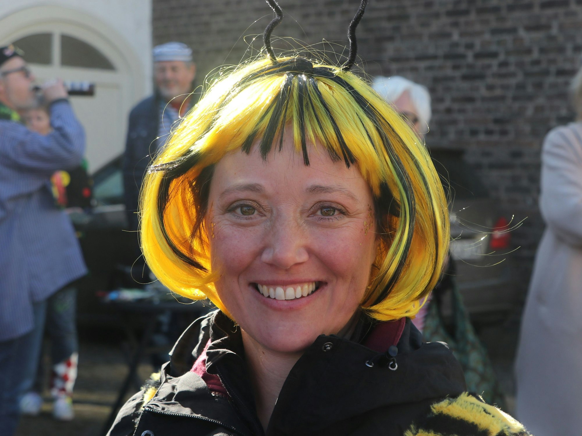 Auf dem Bild ist eine Frau zu sehen, die sich als Biene verkleidet hat und in die Kamera strahlt.