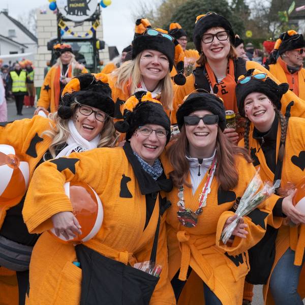 Die Karnevalsgruppe „Wilde Jecken“ aus Oberodenthal lachen im orangefarbenen Kostüm in die Kamera.
