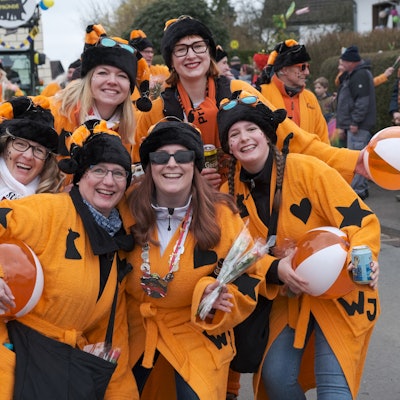 Die Karnevalsgruppe „Wilde Jecken“ aus Oberodenthal lachen im orangefarbenen Kostüm in die Kamera.