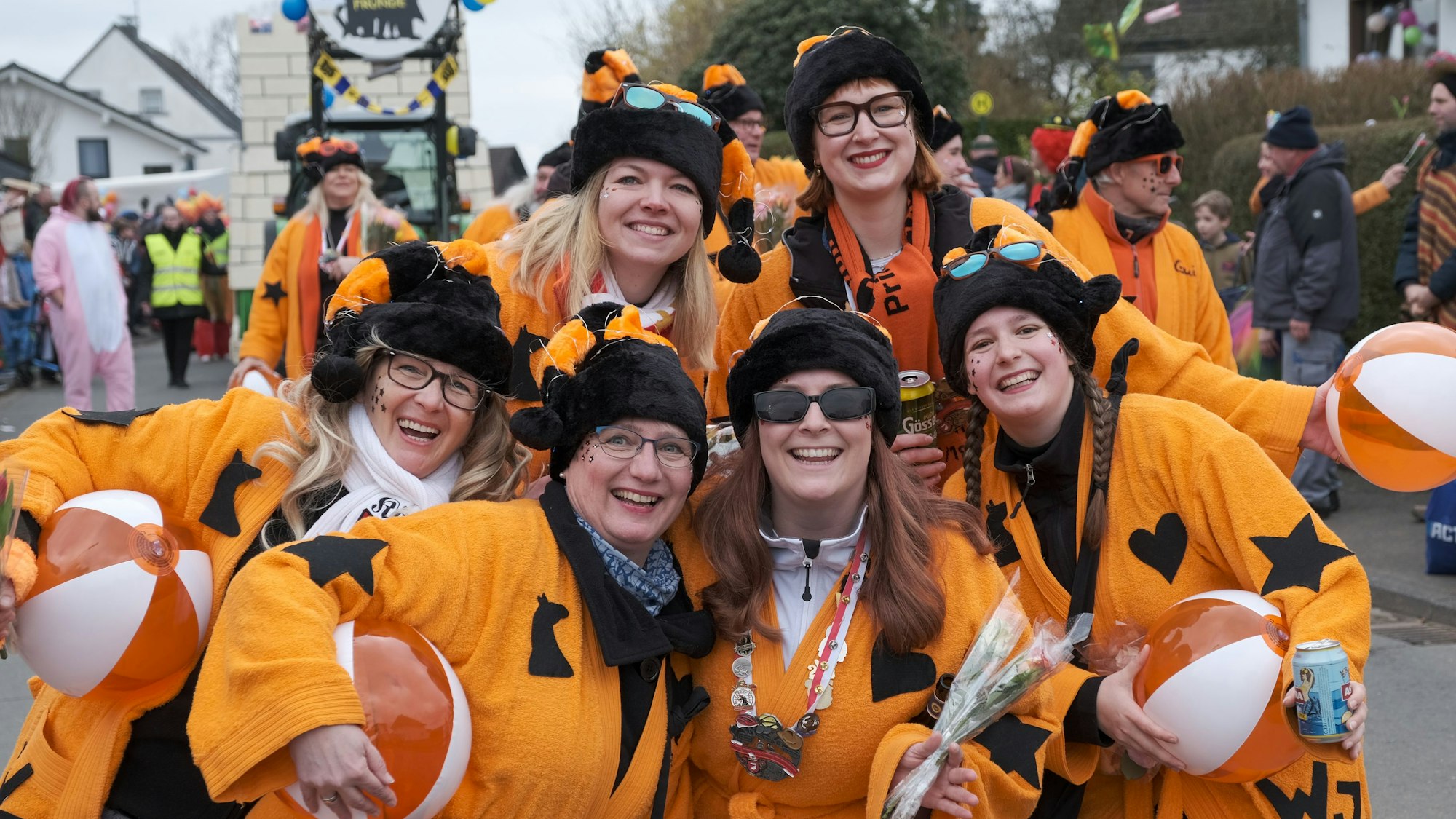 Die Karnevalsgruppe „Wilde Jecken“ aus Oberodenthal lachen im orangefarbenen Kostüm in die Kamera.