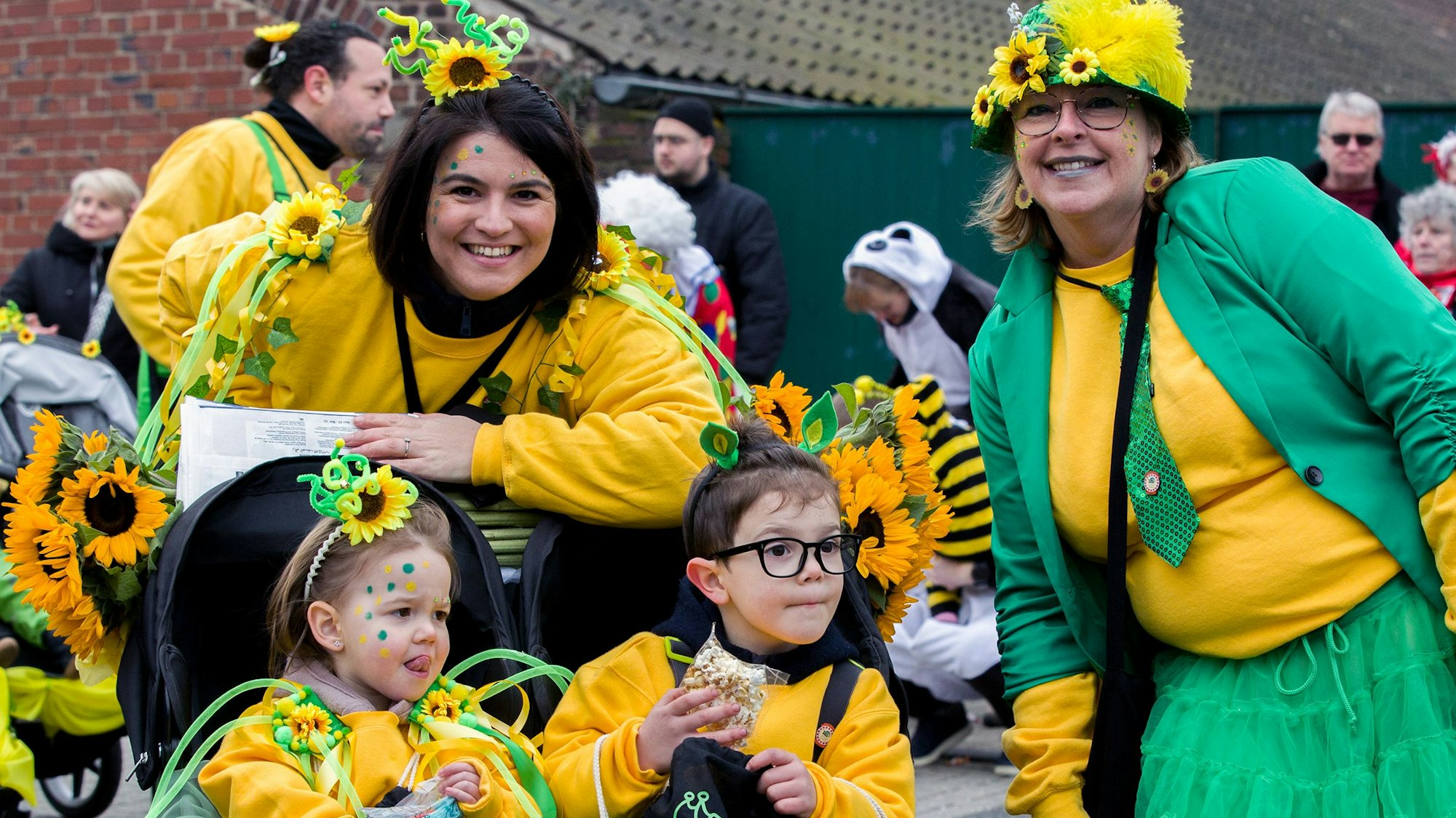 Zwei gelb-grün kostümierte Mütter und ihre beiden Kinder schauen in die Kamera.