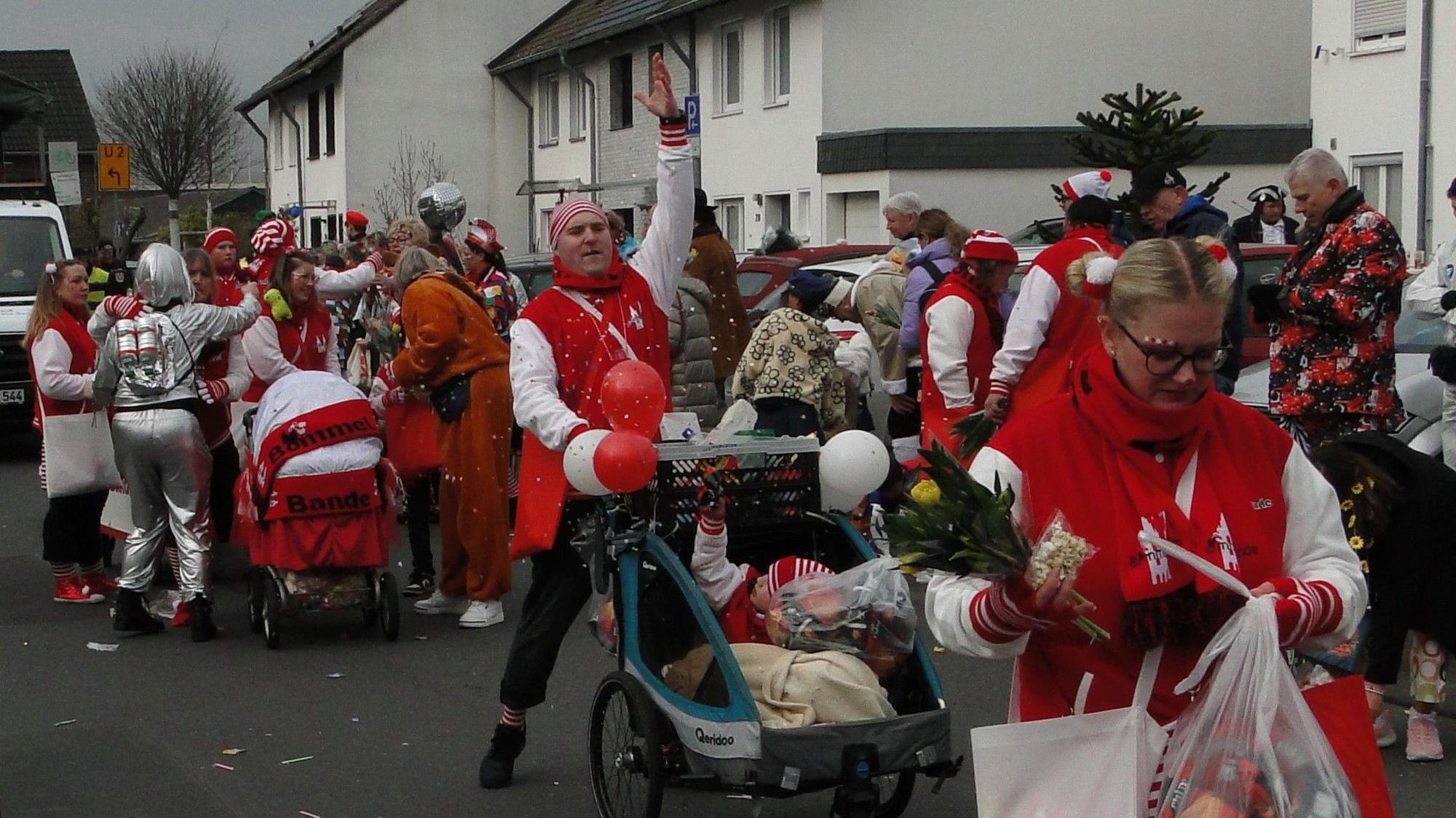 Rot-weiß gekleidete Jecke ziehen durch die Straßen von Merkenich.