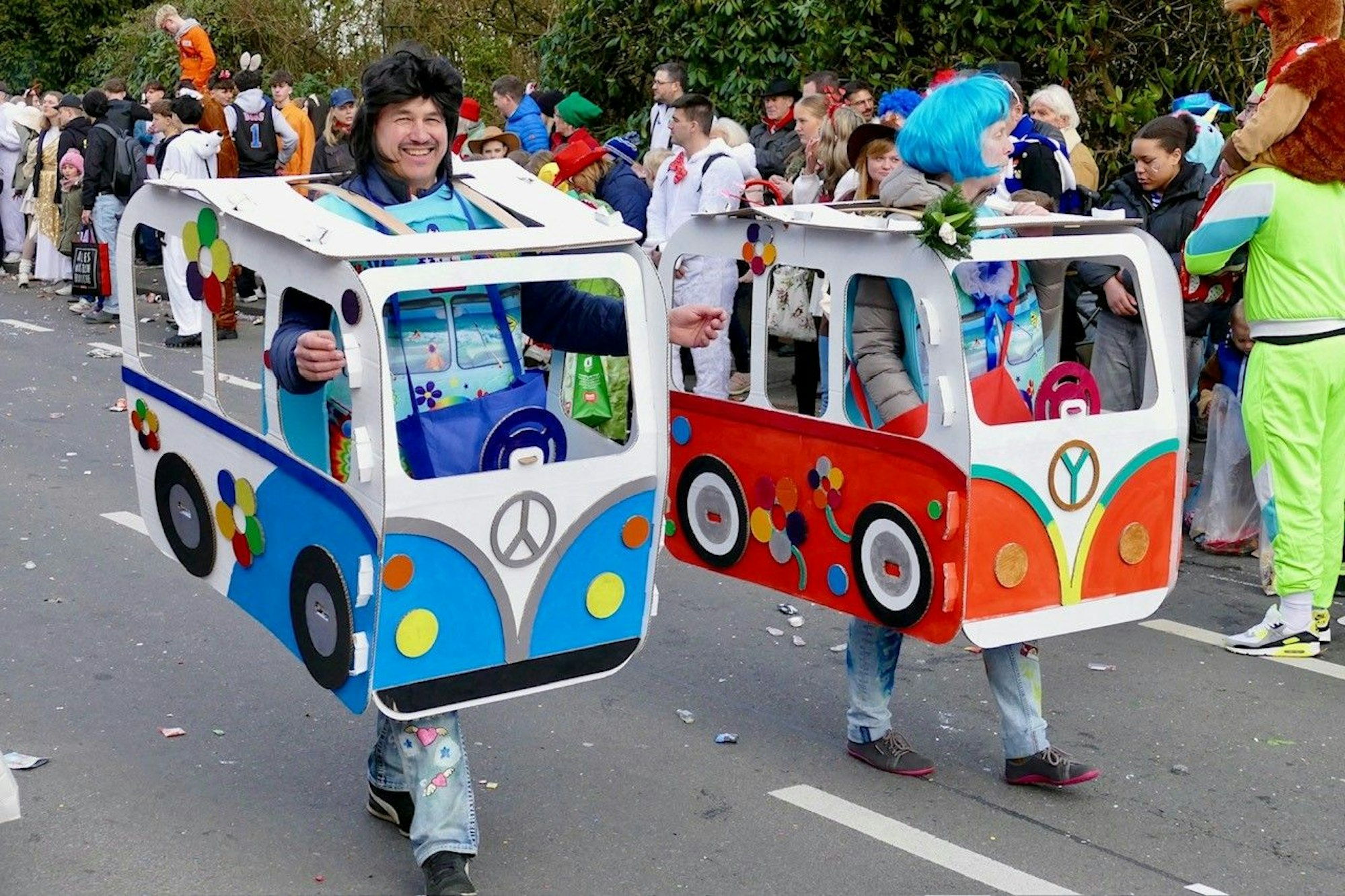 Ein Man und eine Frau tragen gebastelte VW-Busse.