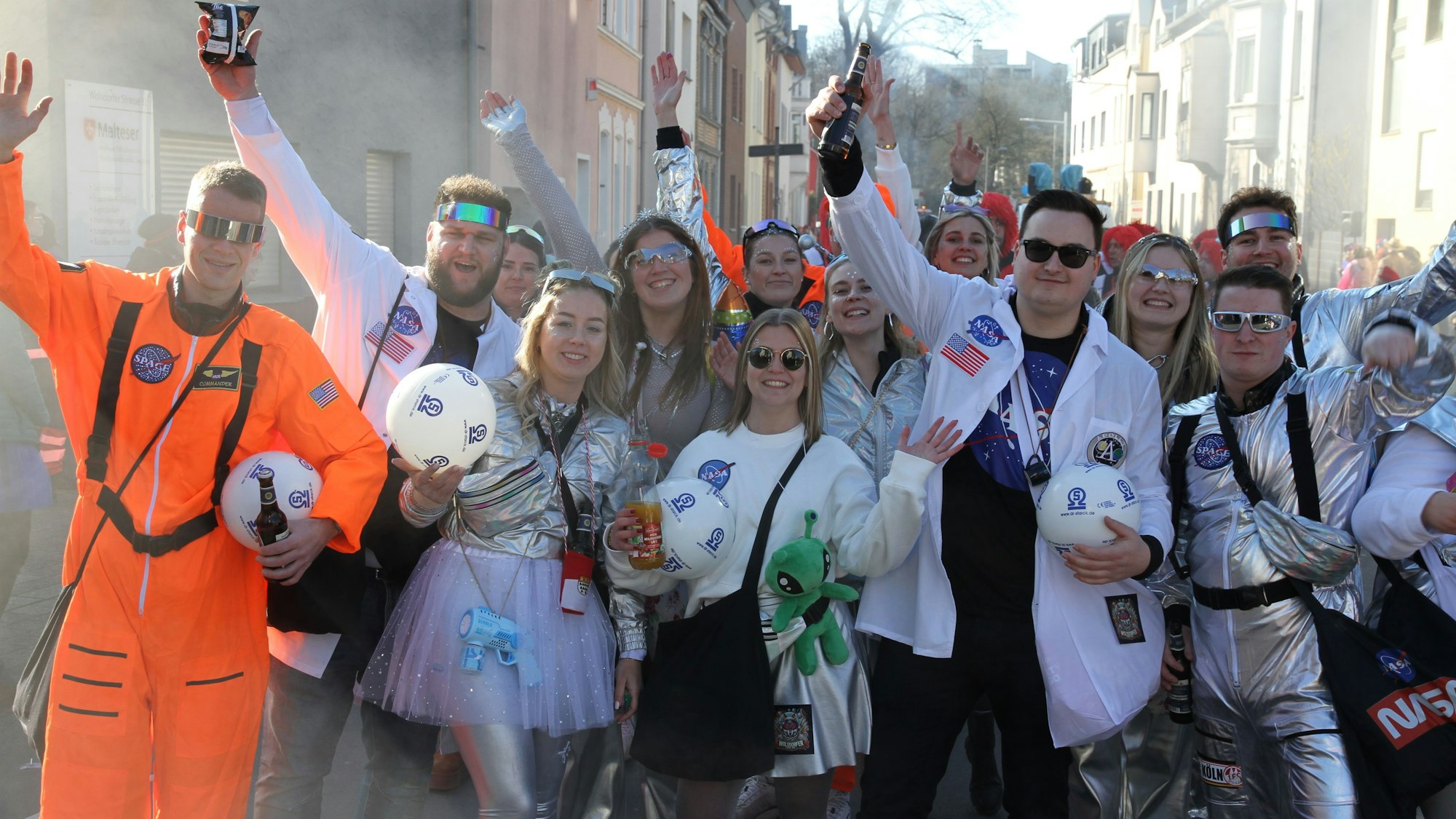 Als Astronauten verkleidetet Frauen und Männer reißen die Arme hoch.
