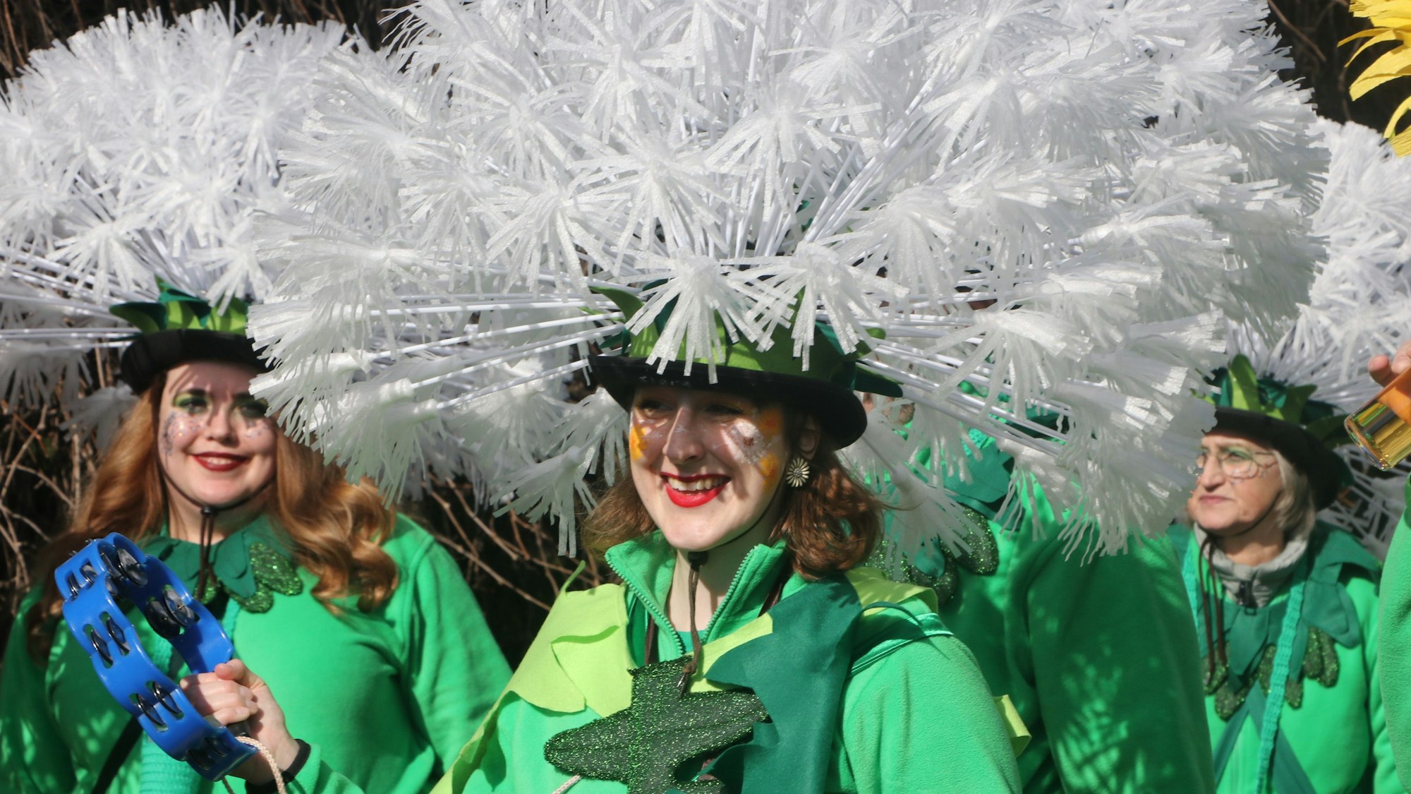 Auf dem Bild sind Frauen zu sehen, die als die Blume Löwenzahn verkleidet sind und einen aufwendigen weißen Blüten-Kopfschmuck tragen