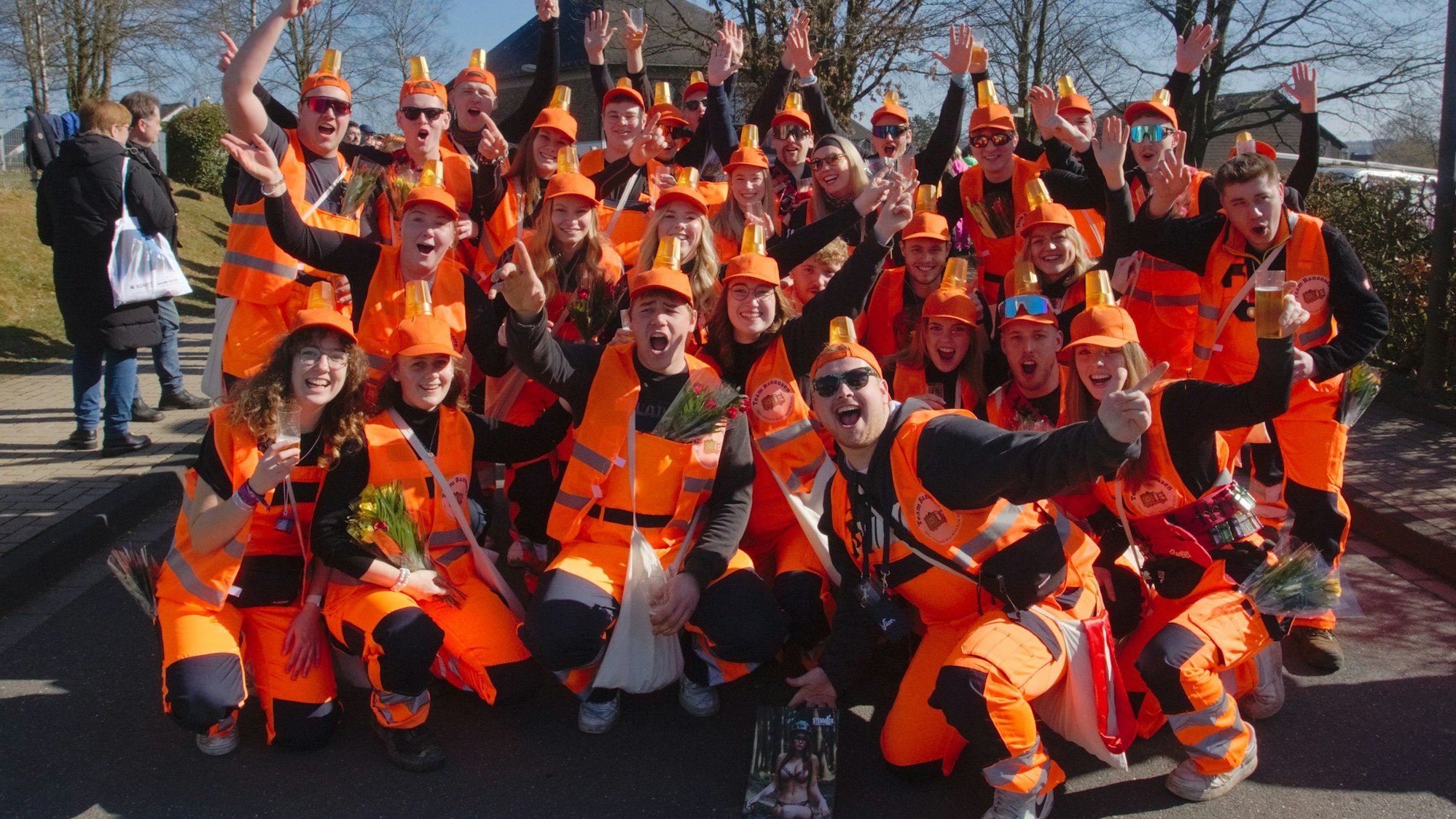 Eine im orangefarbenen Müllabfuhrkostüm verkleidete Gruppe bei einem Karnevalszug.