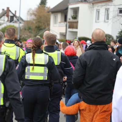 Polizeibeamte gehen durch eine Menge bunt kostümierter Jecken auf der Straße Kaule in Bensberg.