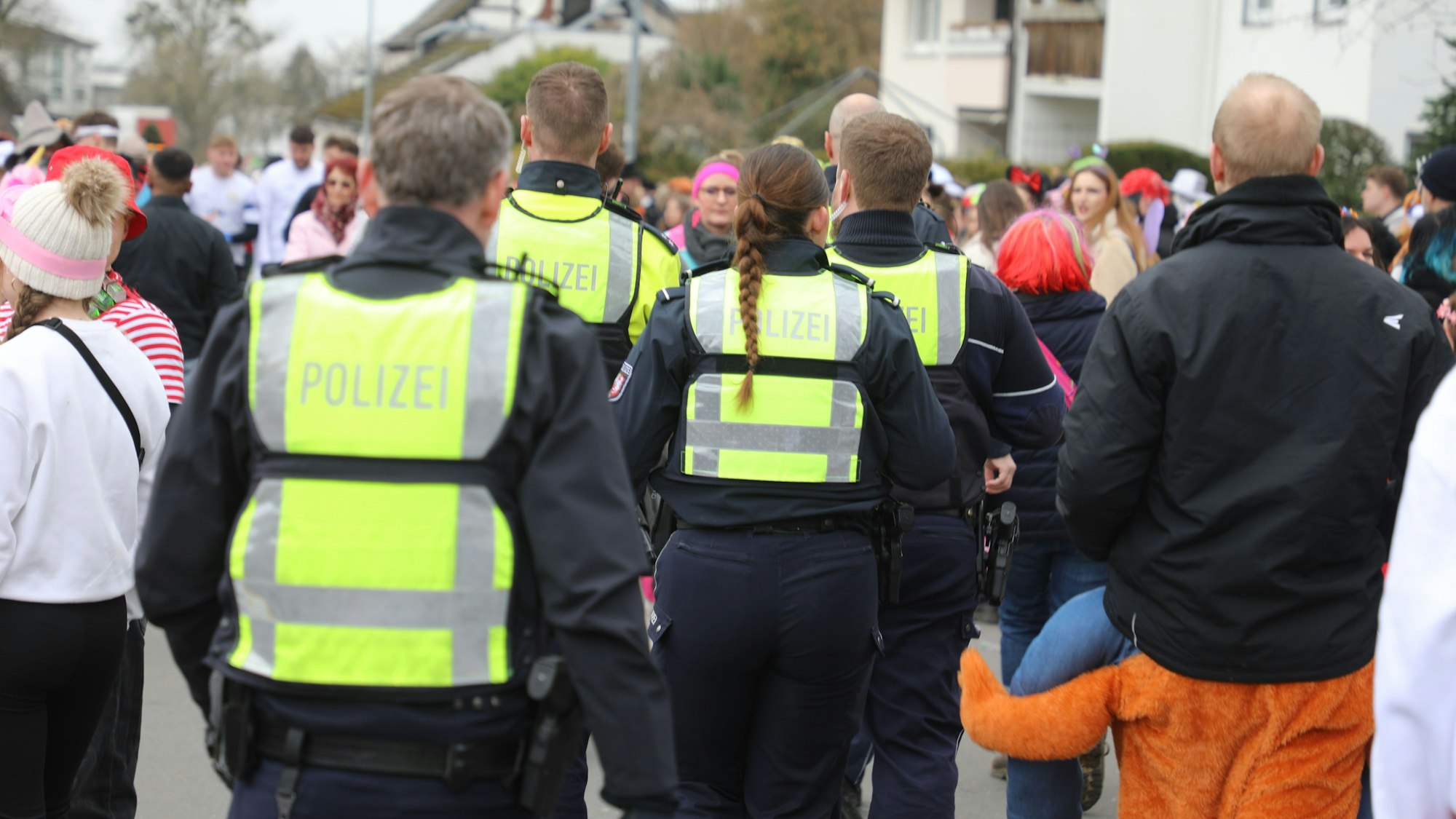 Polizeibeamte gehen durch eine Menge bunt kostümierter Jecken auf der Straße Kaule in Bensberg.