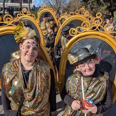 Das Foto zeigt eine Fußgruppe, die große Spiegel auf dem Rücken trägt.