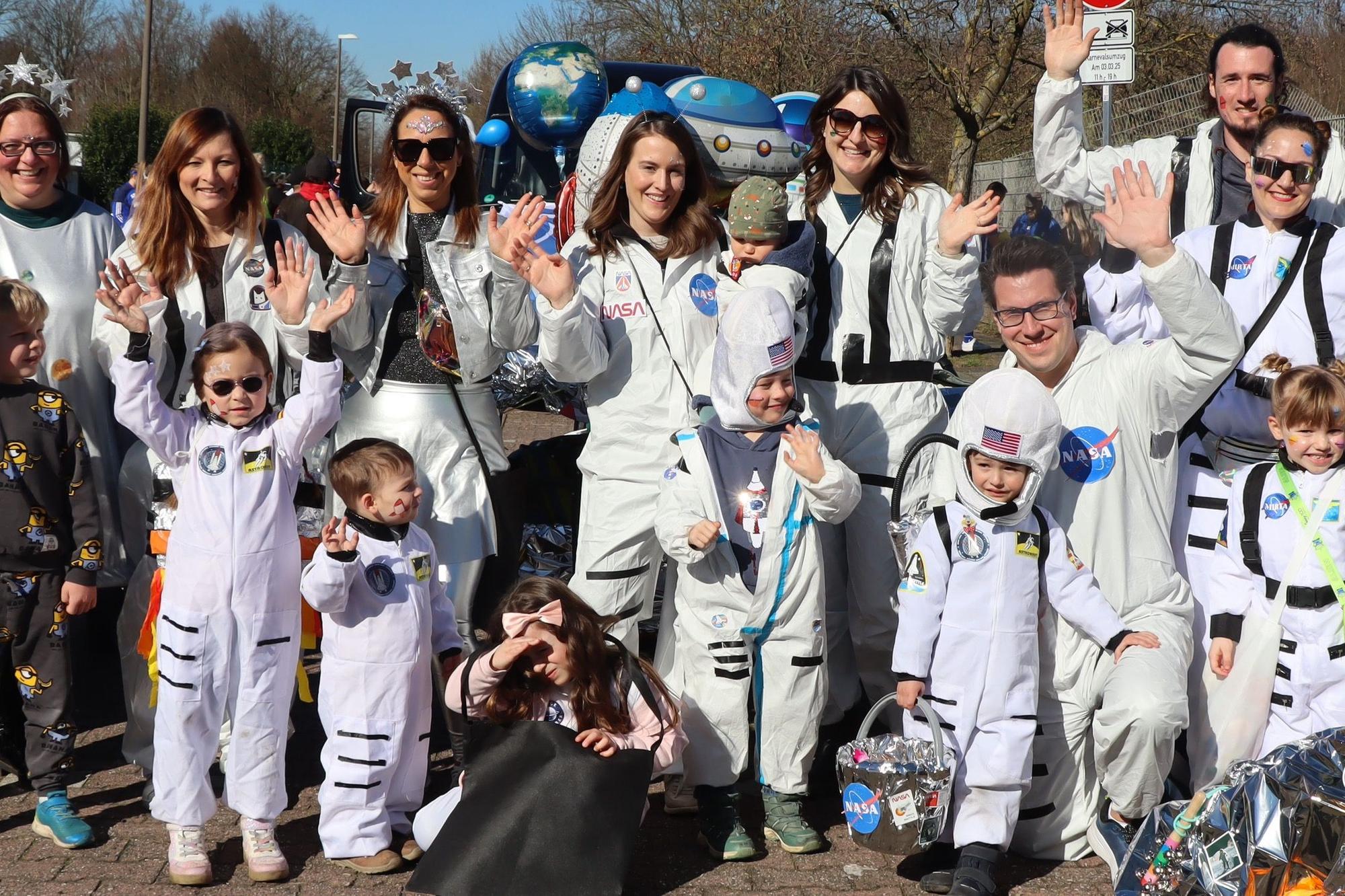 Auf dem Bild sind Eltern und Kinder zu sehen, die sich als Astronauten verkleidet haben.