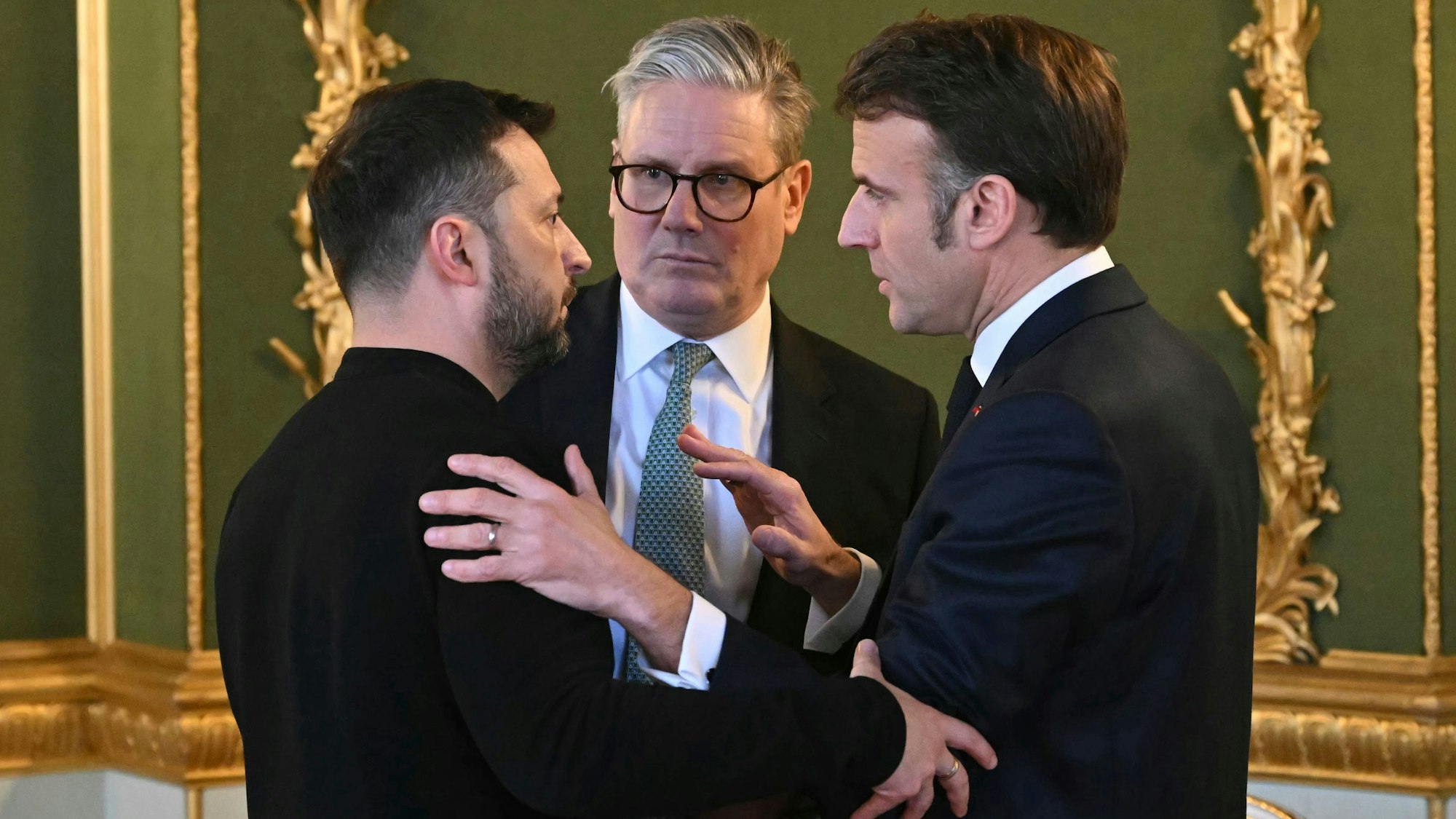 Der britische Premier Sir Keir Starmer (M), der ukrainische Präsident Wolodymyr Selenskyj (l) und der französische Präsident Emmanuel Macron (r) unterhalten sich während des Gipfeltreffens der europäischen Staats- und Regierungschefs zur Lage der Ukraine im Lancaster House.