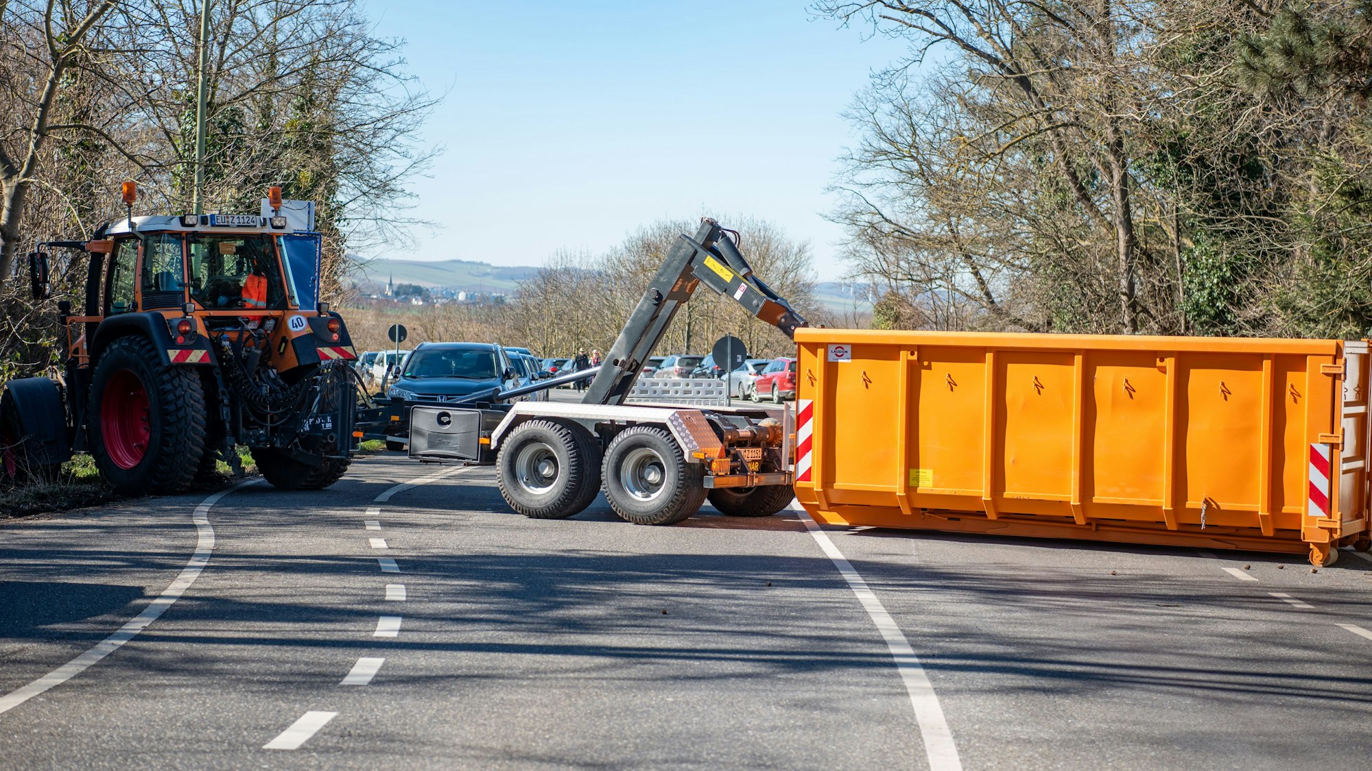 Ein Traktor zieht einen Container quer auf eine Straße.