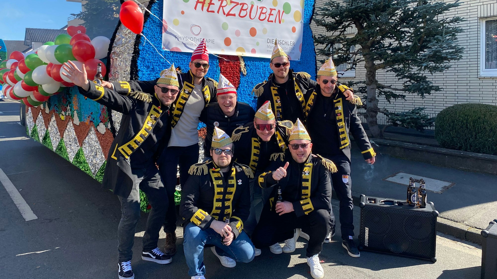 Auf dem Bild ist eine Männergruppe mit Uniformjacken, Narrenkappen und Sonnenbrillen zu sehen.