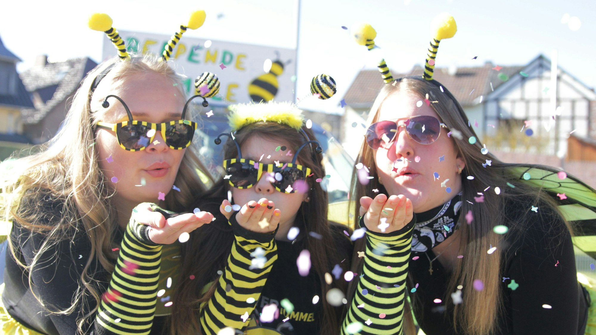 Die Hommele Emily (v.l.), Hannah und Samira verteilen Süßigkeiten und gute Laune unter den Jecken am Wegesrand.