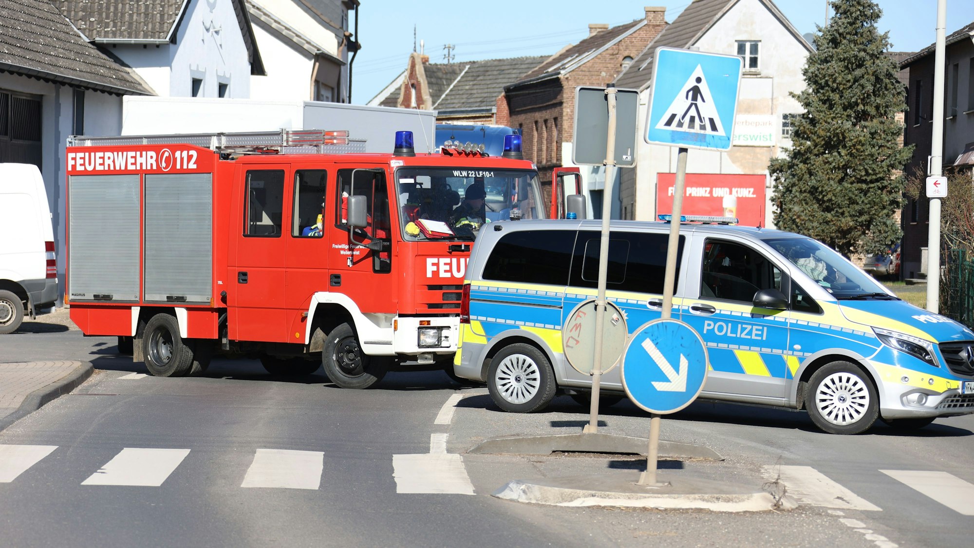 Ein Feuerwehrfahrzeug und ein Polizeiauto sperren eine Straße ab.