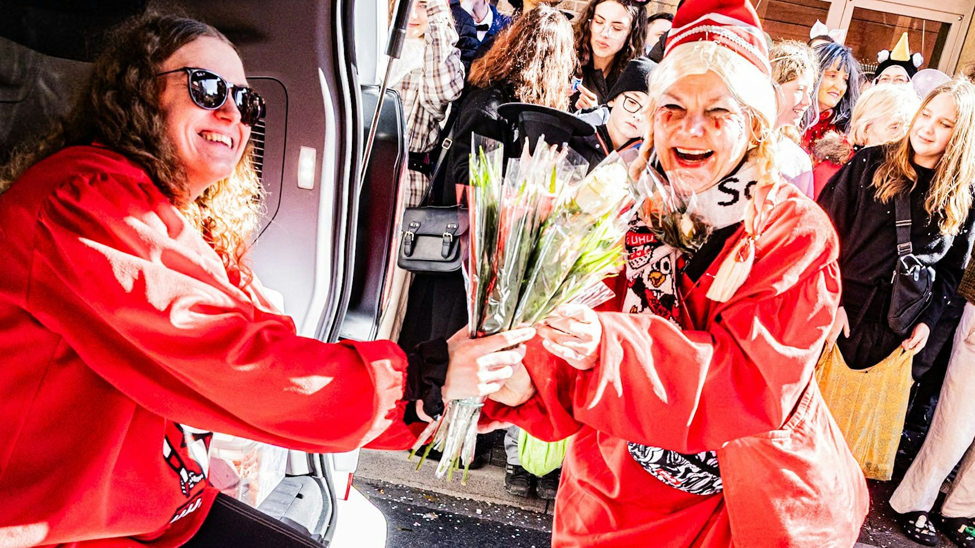 Eine Frau mit Blumen lacht in die Kamera.