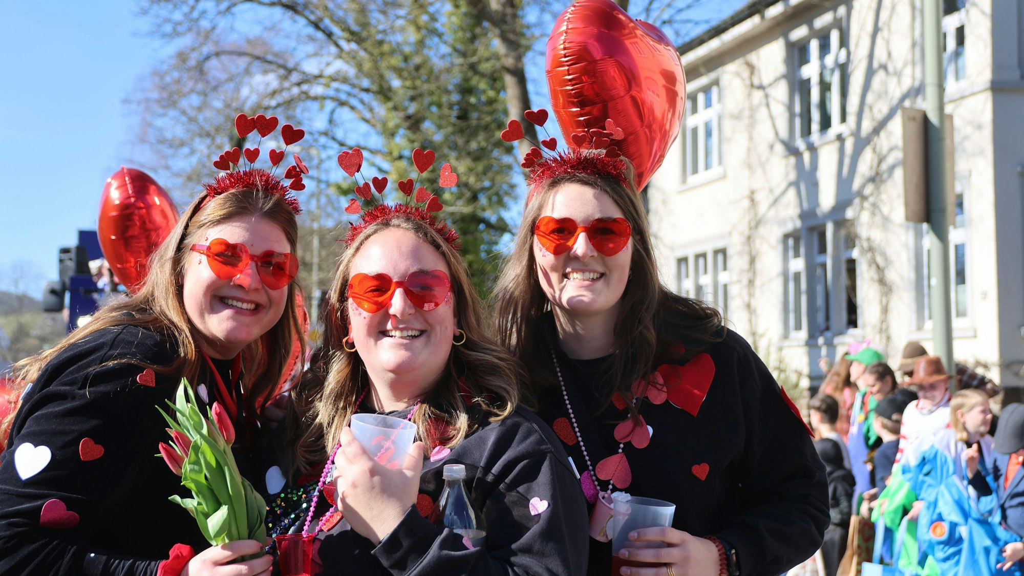 Drei Frauen mit Herzkostümen.