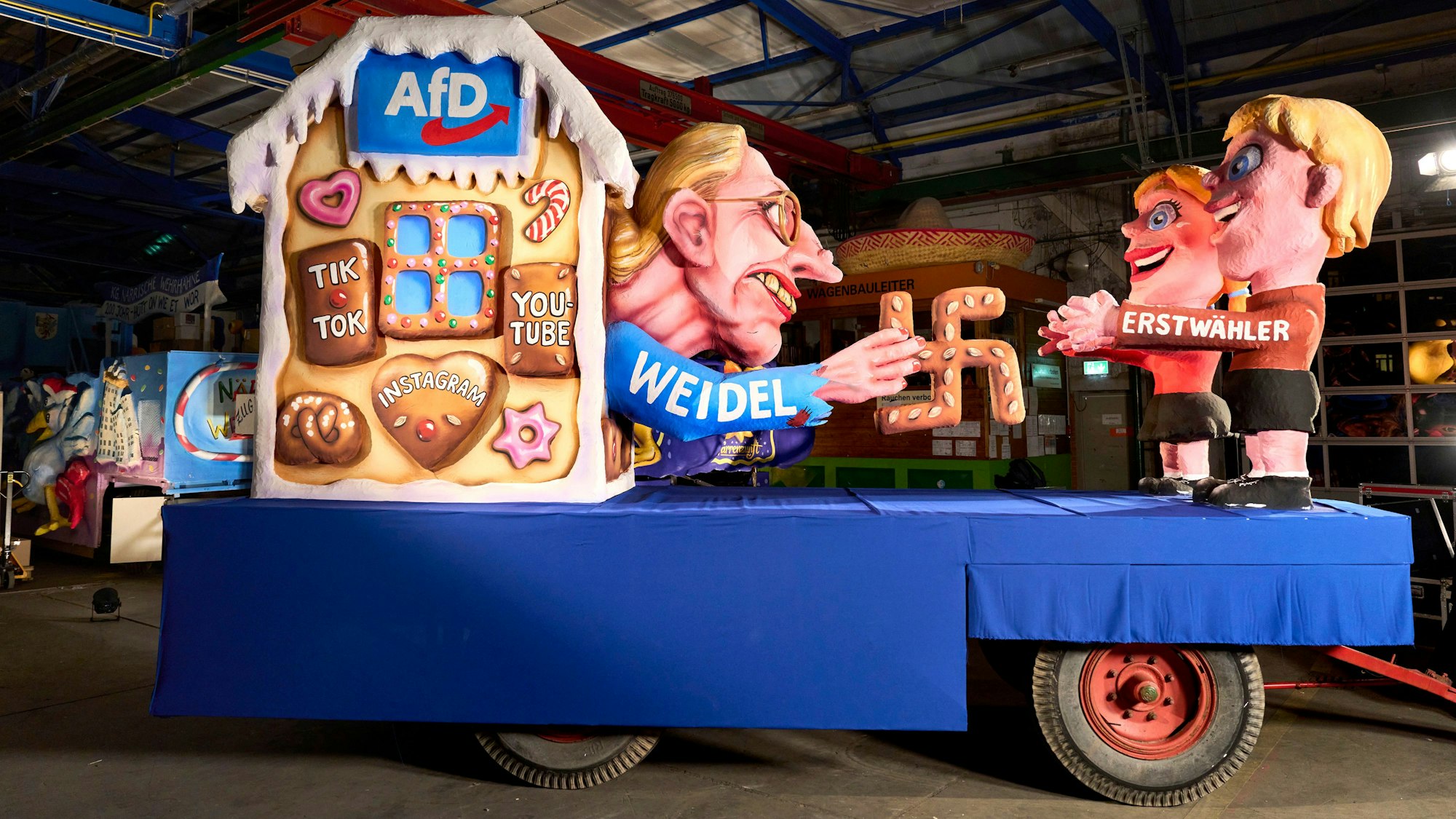 Das Foto zeigt einen Mottowagen der Düsseldorfer Rosenmontagszug mit einem Motiv des Märchens "Hänsel und Gretel": Dort ist AfD-Kanzlerkandidatin Alice Weidel zu sehen, die mit einem Lebkuchen-Hakenkreuz Erstwähler anlockt.