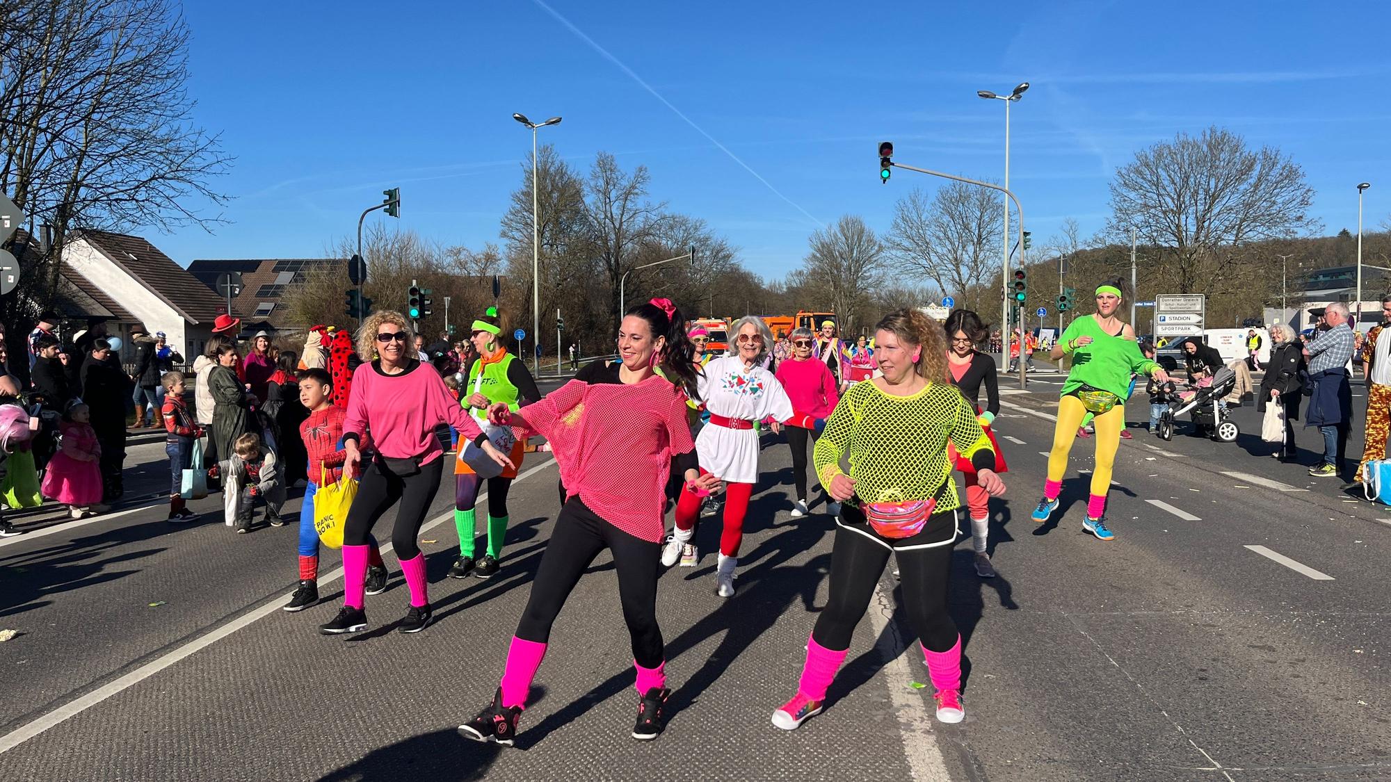 Bunt verkleidete Frauen tanzen auf der Straße Zumba.