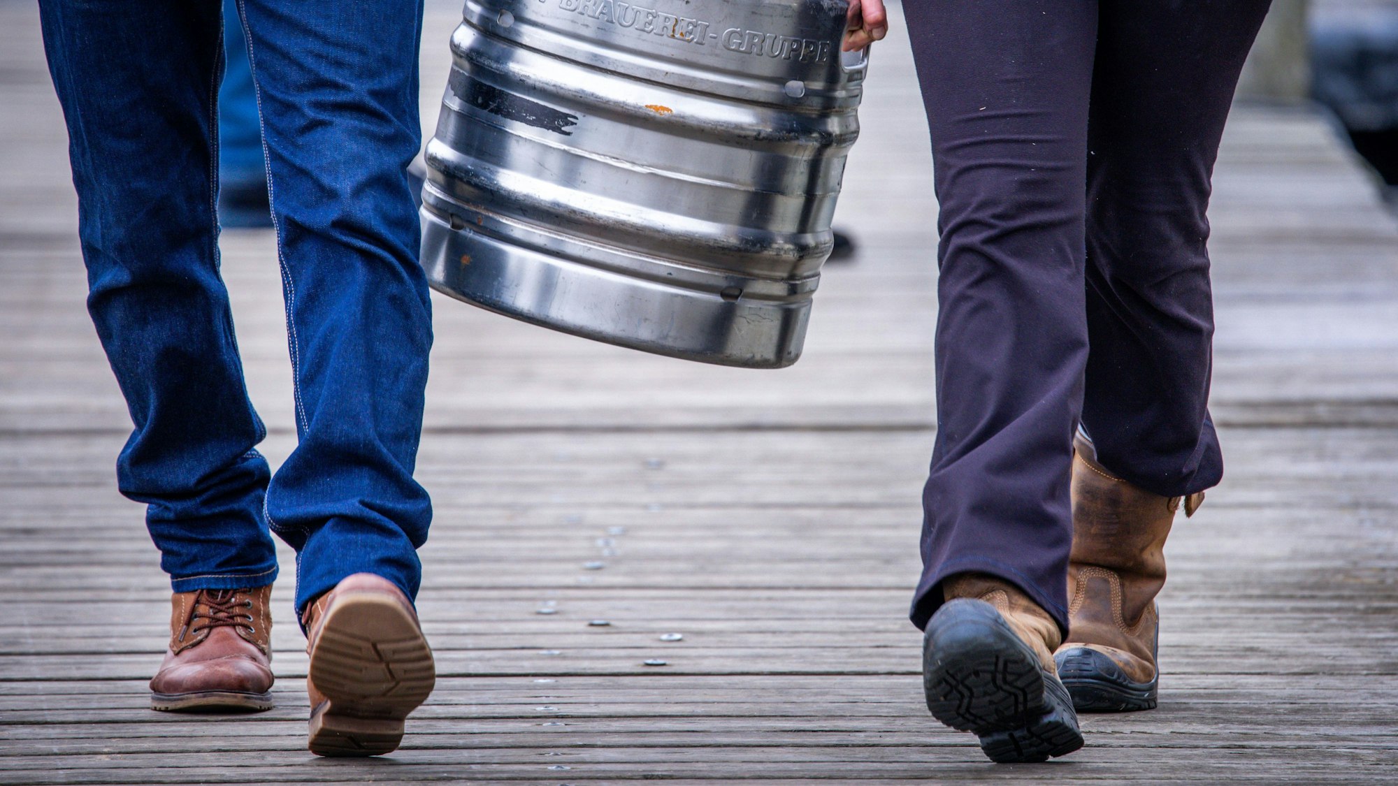 Zwei Personen tragen ein Fass Bier zwischen sich.