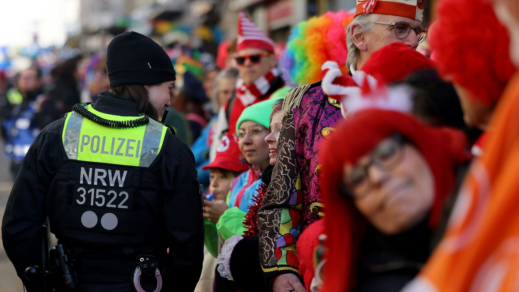 Polizei spricht mit Karnevalisten am Straßenrand.