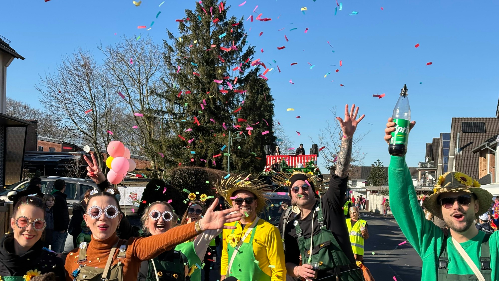 Verkleidete Gärtnerinnen und Gärtner, die Sonnenbrillen tragen, schmeißen mit Konfetti auf der Straße.