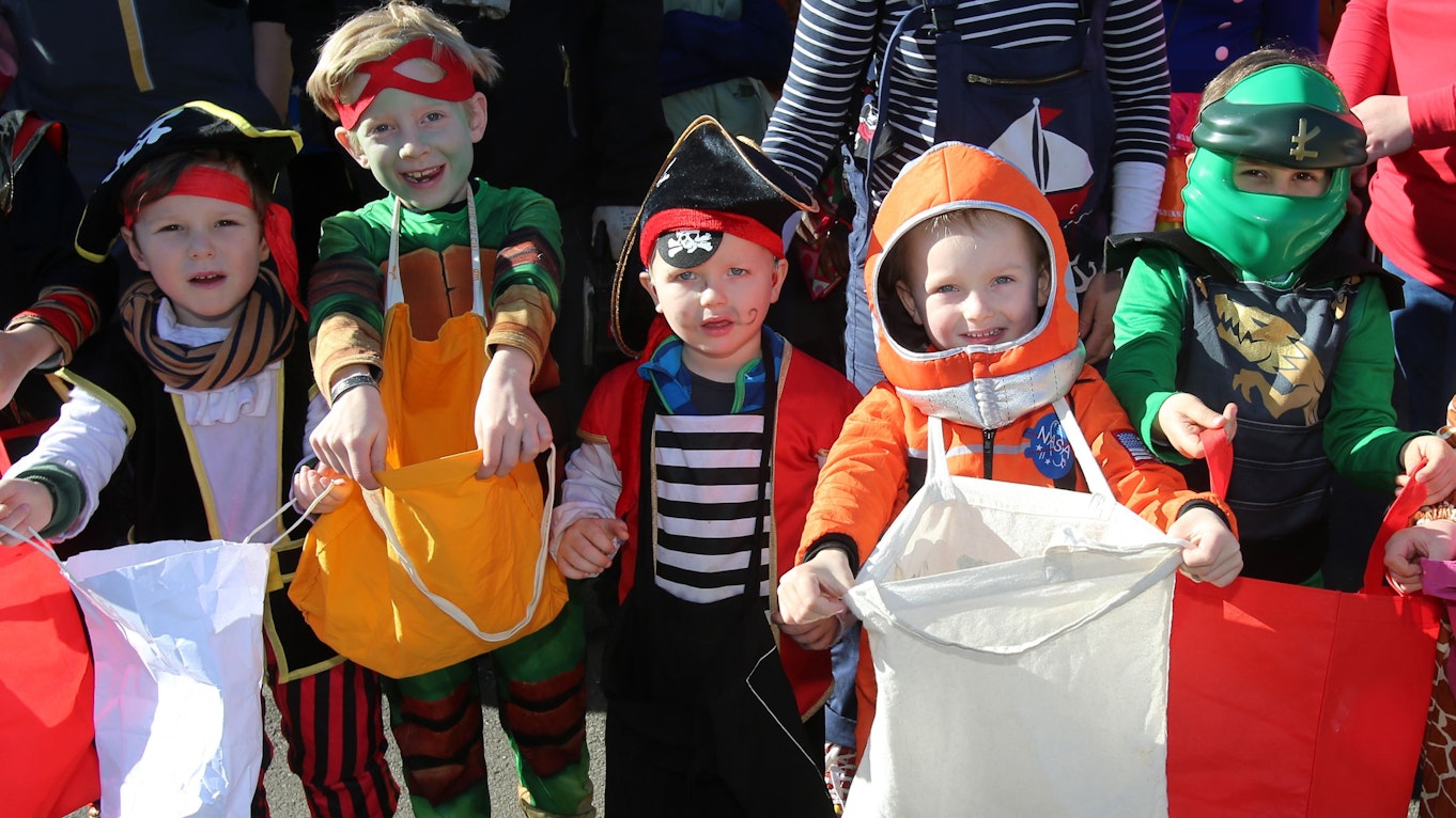 Kinder rufen am Rand eines Karnevalszugs „Kamelle“.