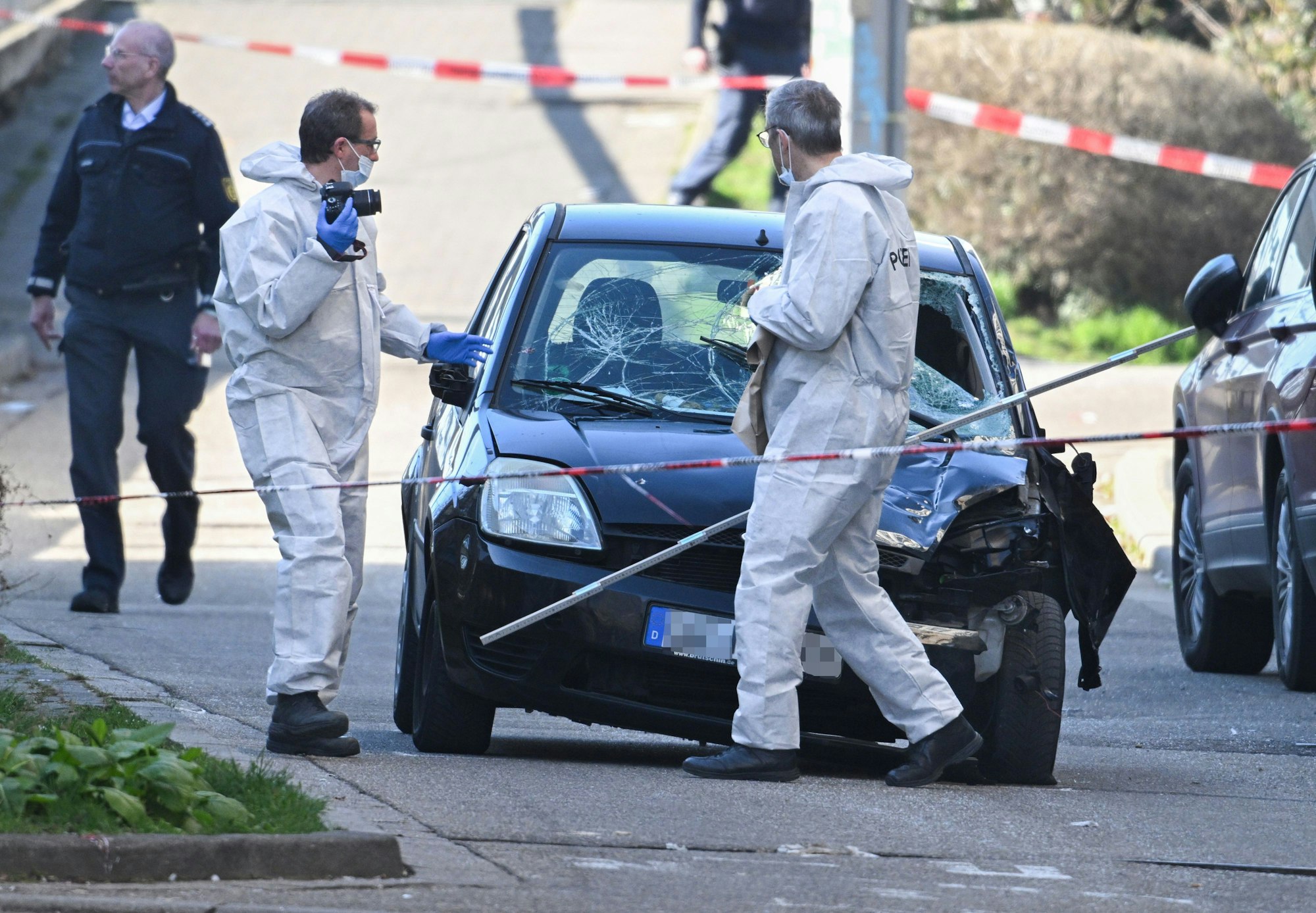 03.03.2025, Baden-Württemberg, Mannheim: Beamte der Spurensicherung untersuchen ein beschädigtes Fahrzeug an einer Zufahrt zur Rheinbrücke. Nach einem Vorfall mit einem Auto in der Mannheimer Innenstadt mit mindestens einem Toten und mehreren Verletzten ist der mutmaßliche Fahrer nach Polizeiangaben festgenommen worden. Nach Polizeiangaben war ein Fahrzeug in eine Menschenmenge gefahren. Foto: Boris Roessler/dpa +++ dpa-Bildfunk +++