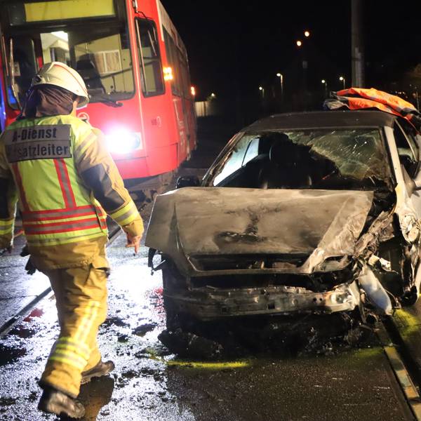 Das Bild zeigt Einsatzkräfte der Feuerwehr an einem ausgebrannten Auto.