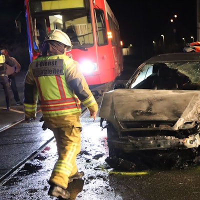 Das Bild zeigt Einsatzkräfte der Feuerwehr an einem ausgebrannten Auto.