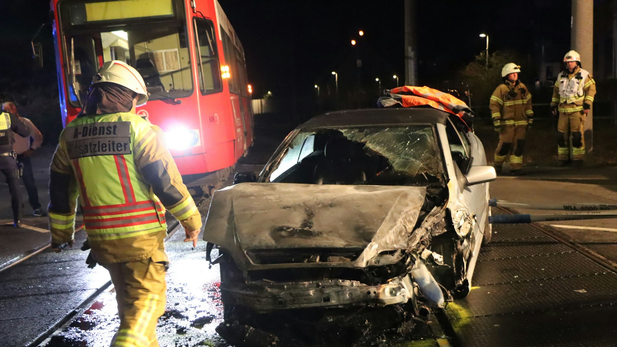 Das Bild zeigt Einsatzkräfte der Feuerwehr an dem ausgebrannten Auto.