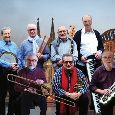 Das Foto zeigt die Musiker mit Instrumenten vor der Kulisse aus Rhein, Rheinbrücke und Domspitzen in Köln.