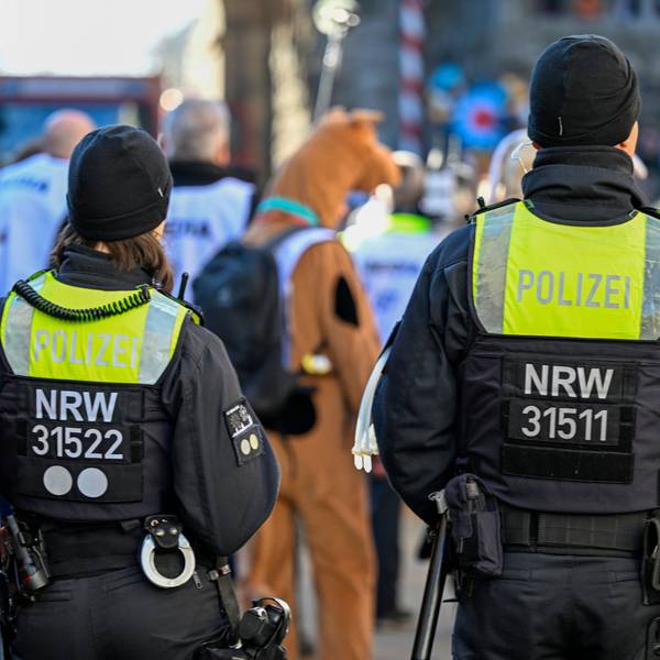 Zwei Polizisten sind am Rande eines Karnevalszuges zu sehen.
