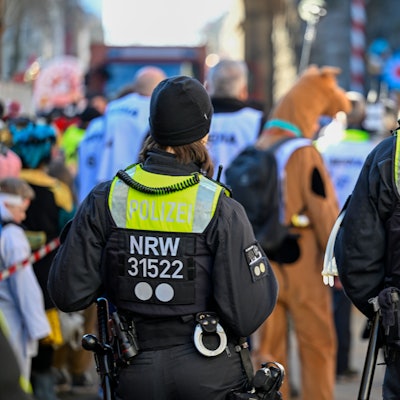 Zwei Polizisten sind am Rande eines Karnevalszuges zu sehen.