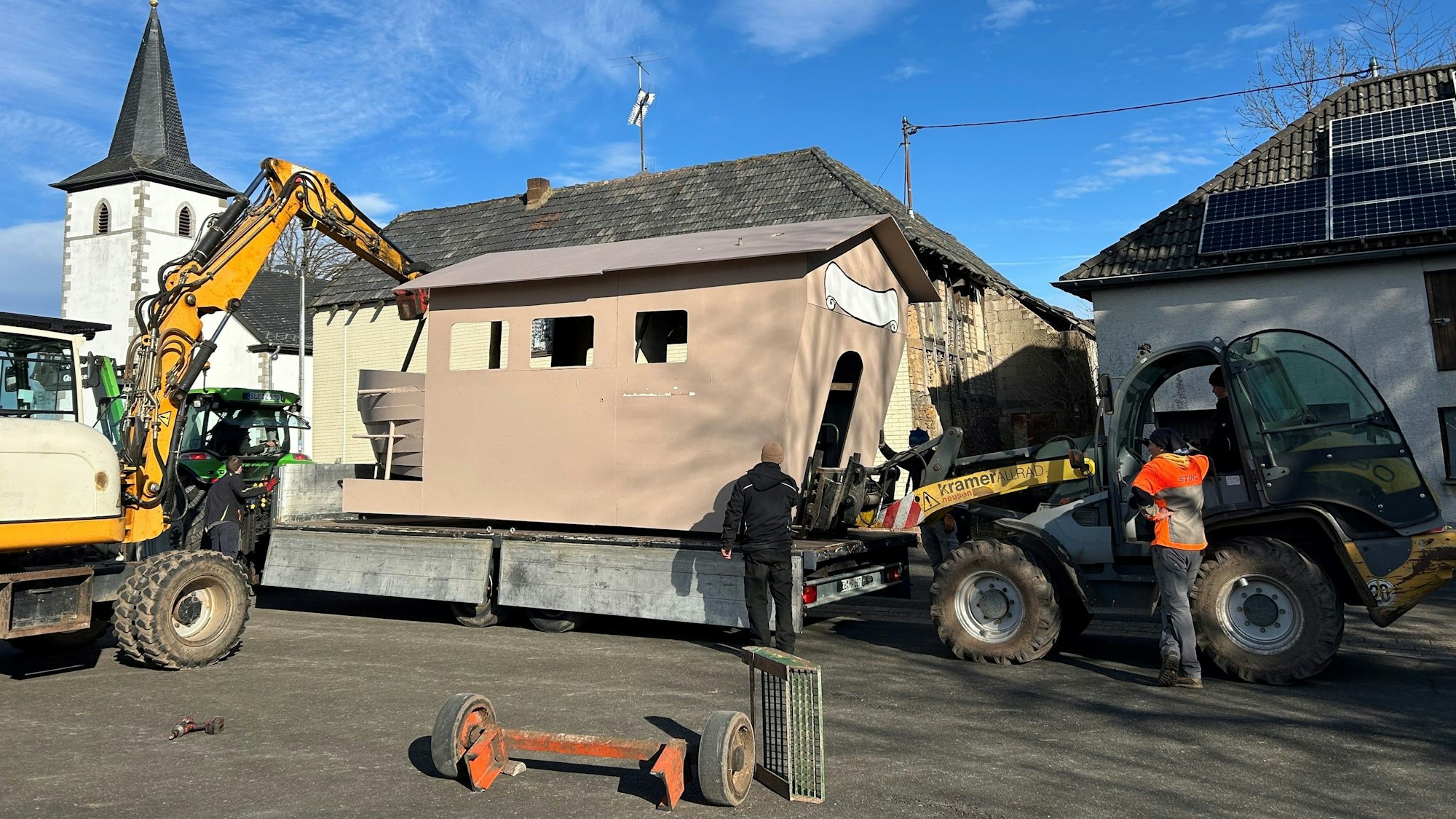 Ein Karnevalswagen wird in Nettersheim-Roderath mit Baggern auf einen neuen  fahrbahren Untersatz gehoben.